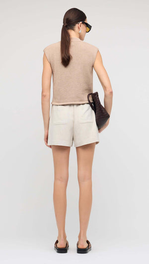 Back view of a model wearing a Beige Sleeveless Knit Top paired with linen shorts.