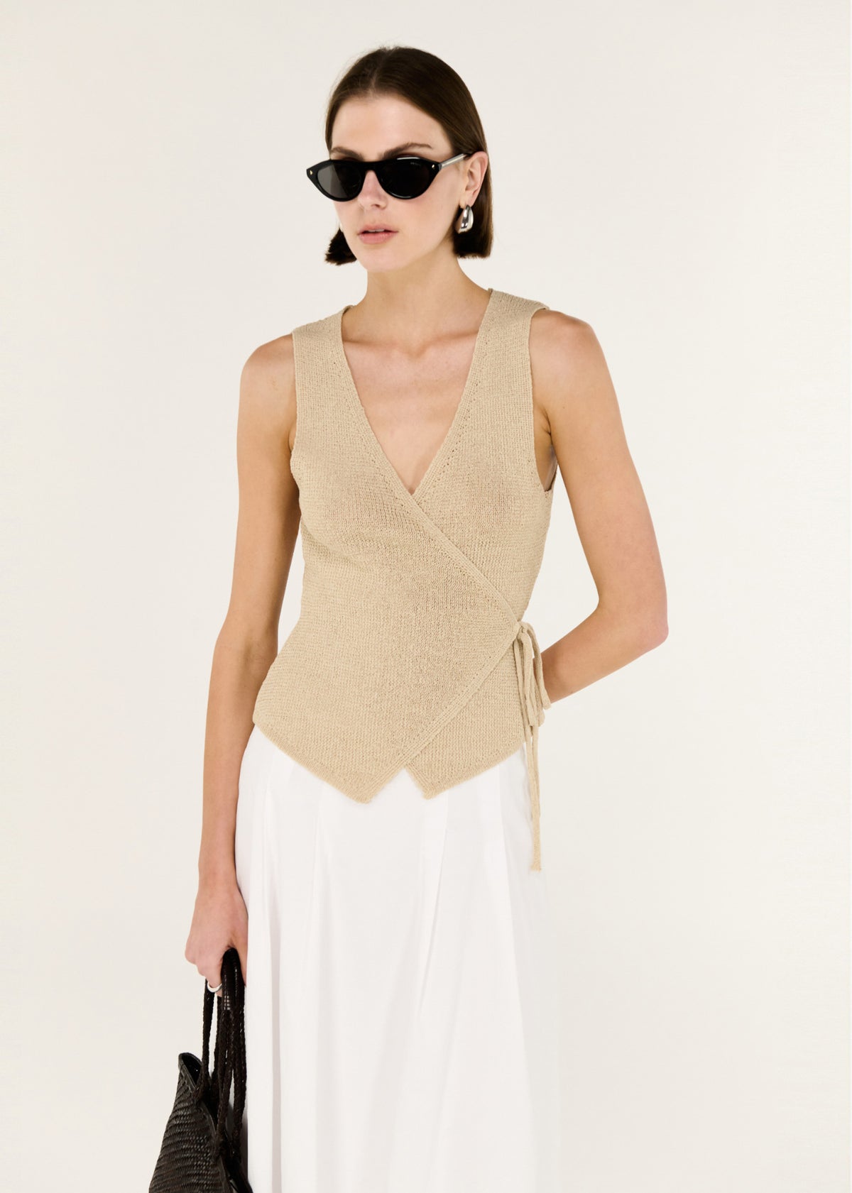 Close-up of the Beige V-neck Wrap Knit Top, showing a sleeveless wrap silhouette and a deep V neckline.