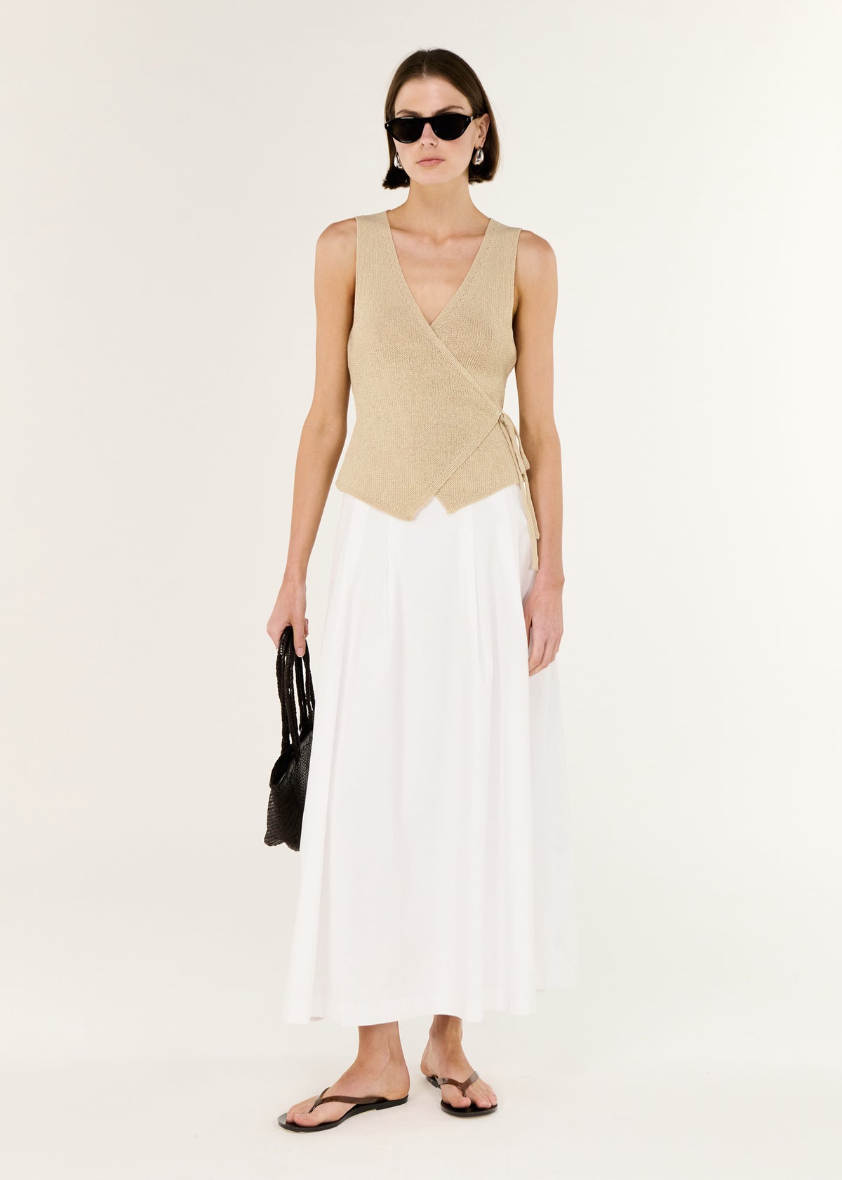 Model wearing Beige V-neck Wrap Knit Top, showing a sleeveless wrap silhouette and a deep V neckline.