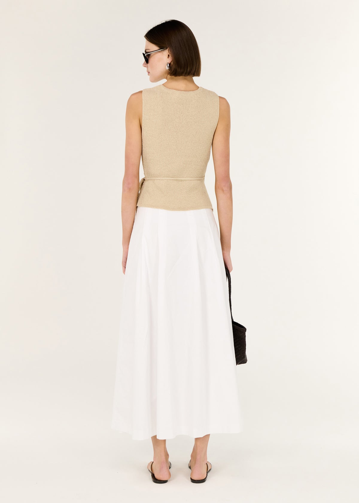 Back view of the Beige V-neck Wrap Knit Top with an adjustable side tie closure and a sleeveless wrap silhouette.