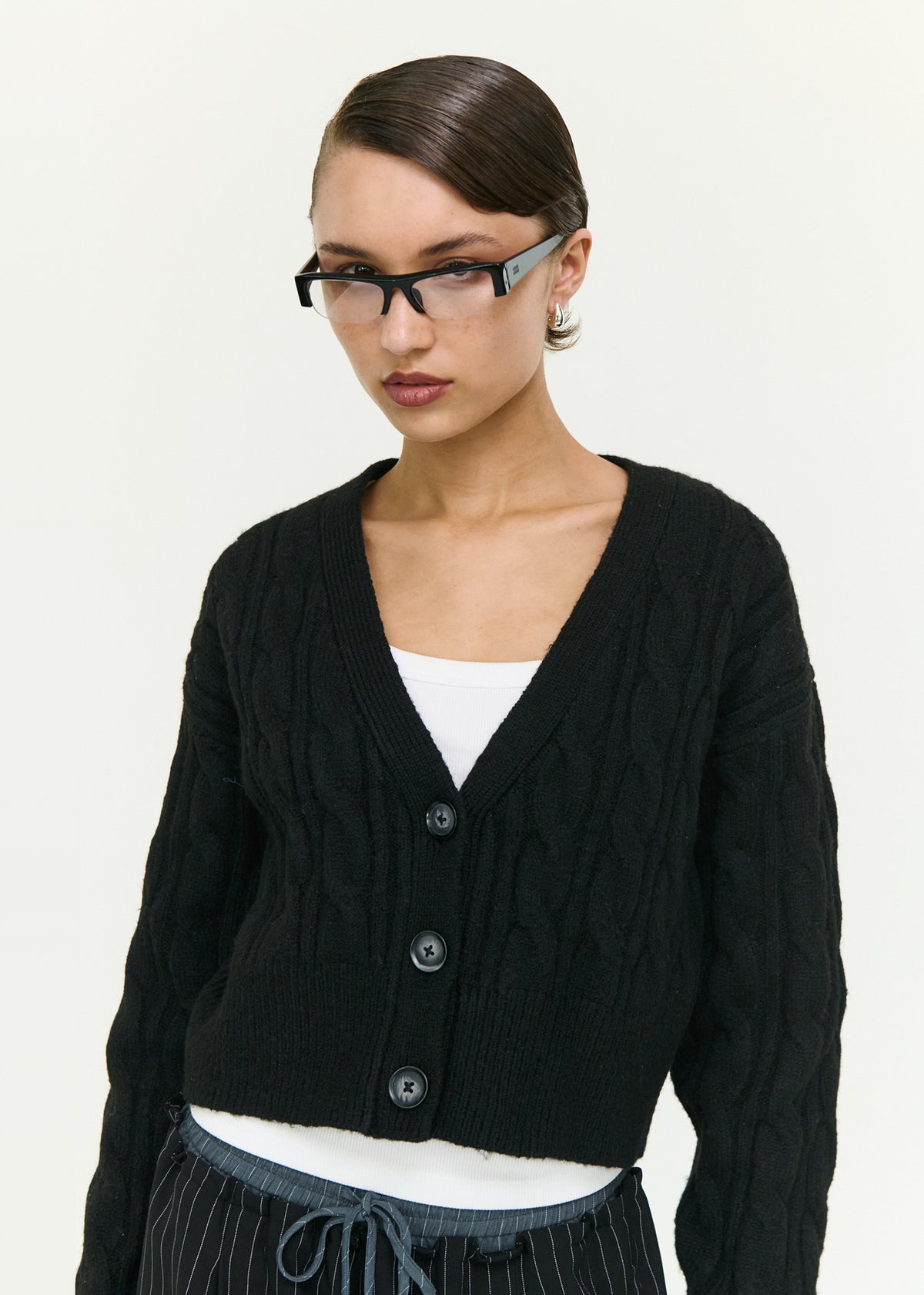 Close-up of the Black Cable Knit Cropped Cardigan, showing a deep V-neckline and a front button closure.