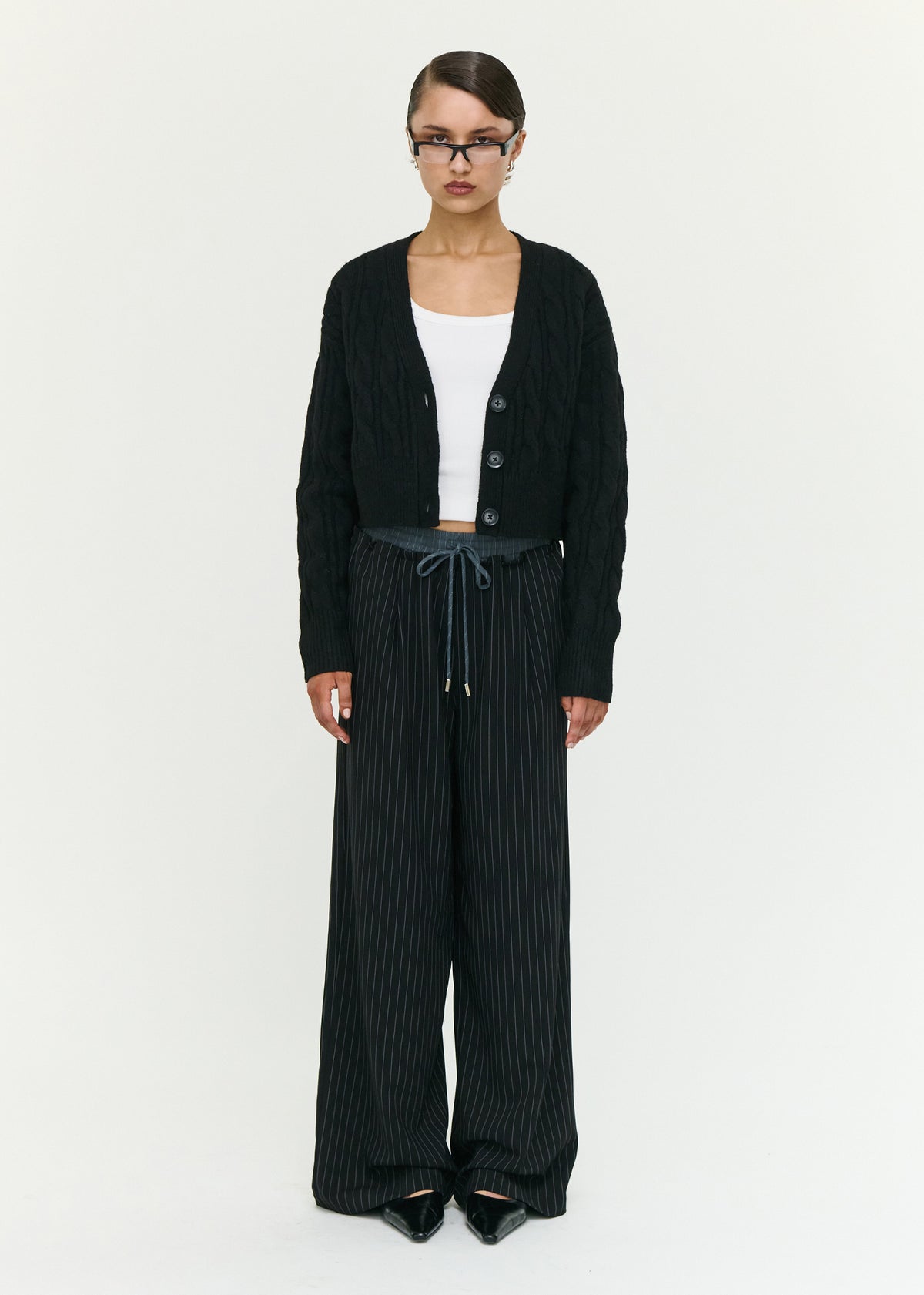 Model wearing Black Cable Knit Cropped Cardigan with a deep V-neckline and a front button closure.