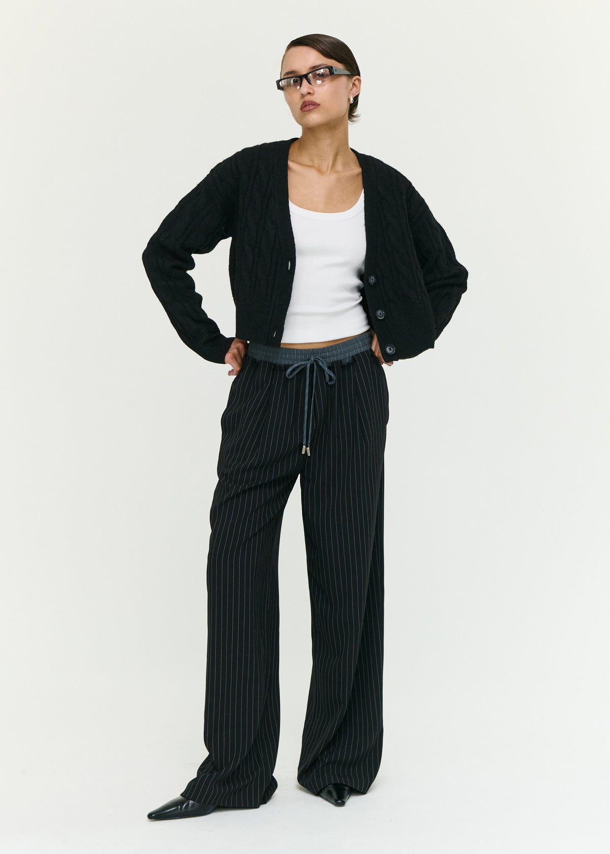 Model wearing Black Cable Knit Cropped Cardigan, showing a ribbed cuffs and hem.