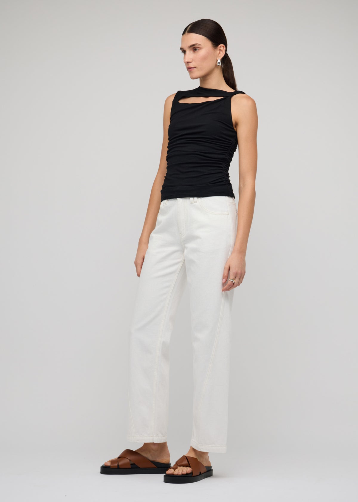 Model wearing Black Cut Out Ruched Top With Bead Detail with a black and an asymmetrical neckline with cut-out detail, turned to the side.