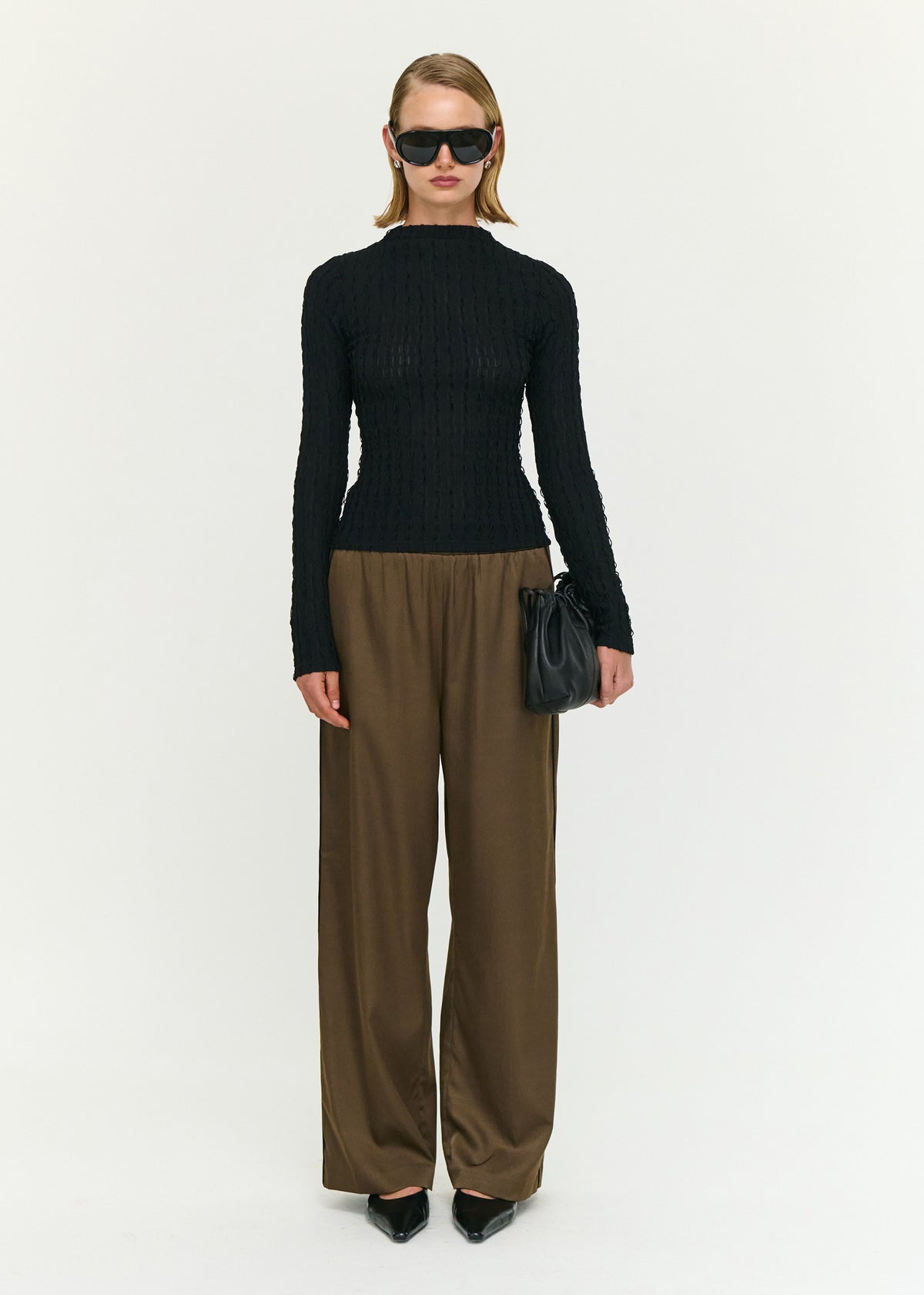 Model wearing Black High Neck Crinkle Stitch Top with a slim fit silhouette and long sleeves.