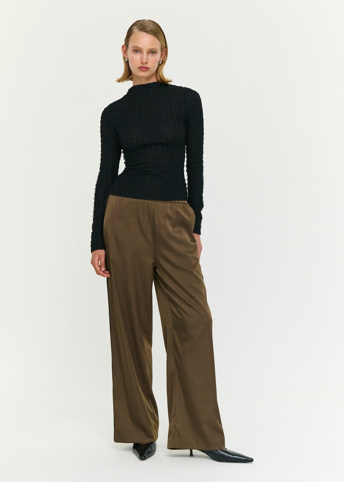 Model wearing Black High Neck Crinkle Stitch Top with a pull-on style and a textured stretch fabrication, turned to the side.