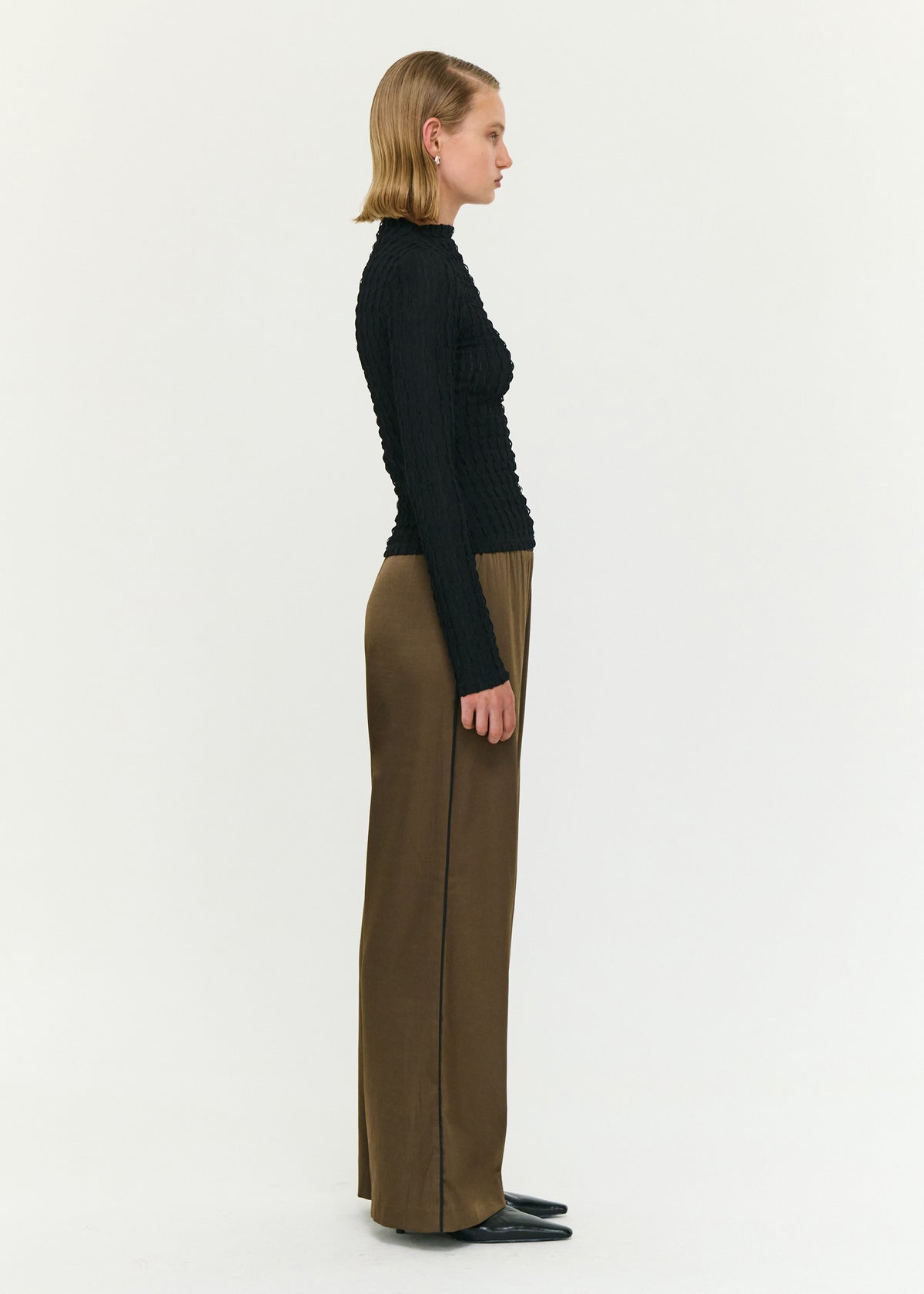 Side view of the Black High Neck Crinkle Stitch Top, showing a high neckline and a slim fit silhouette.