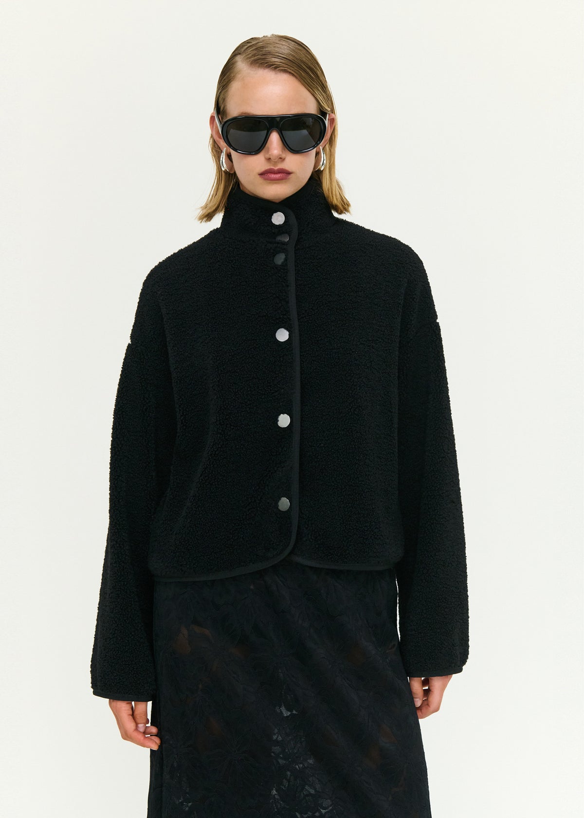 Close-up of the Black High Neck Cropped Sherpa Jacket, showing a stand collar neckline and a snap button front closure.