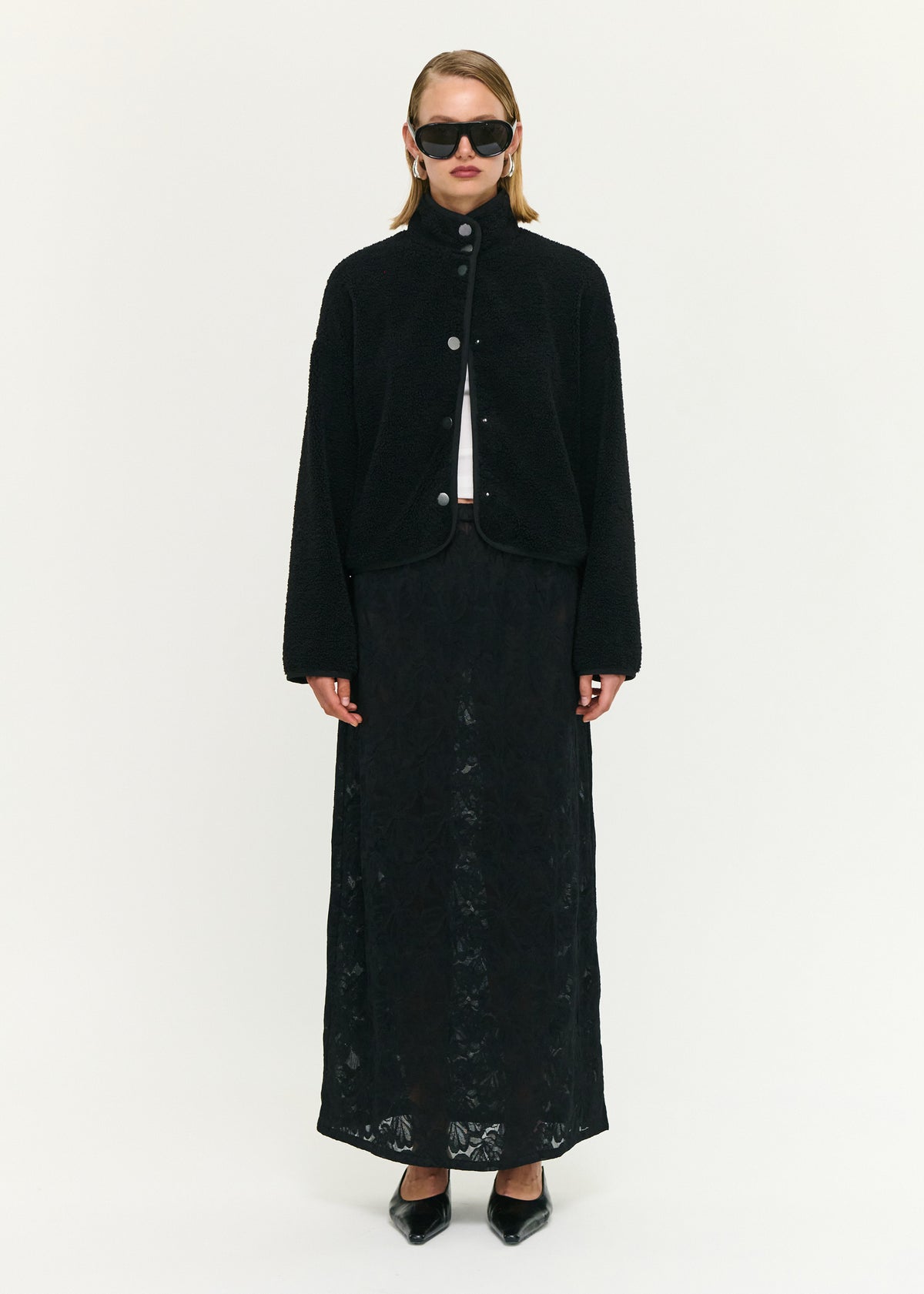 Model wearing Black High Neck Cropped Sherpa Jacket with a stand collar neckline and a snap button front closure.