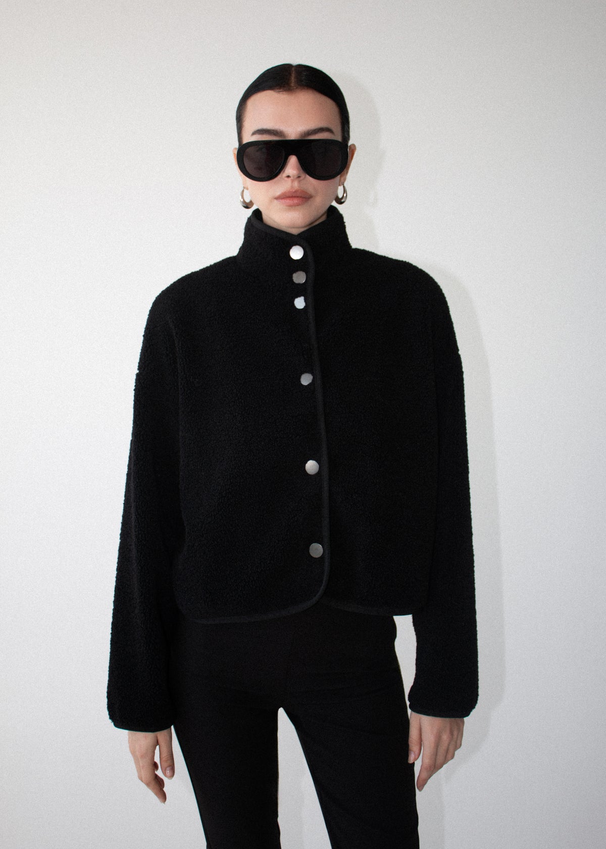 Model wearing Black High Neck Cropped Sherpa Jacket, showing long sleeves and a clean, minimal finish.