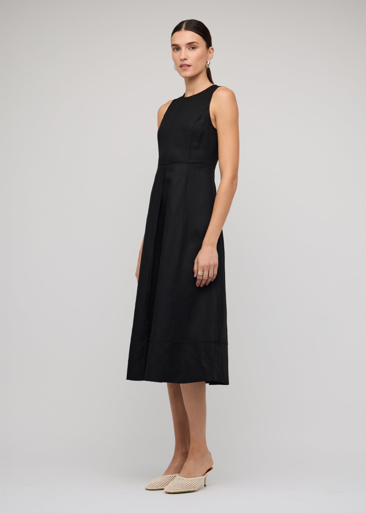 Model wearing Black Linen A-Line Midi Dress with a concealed back zip closure and side seam pockets, turned to the side.
