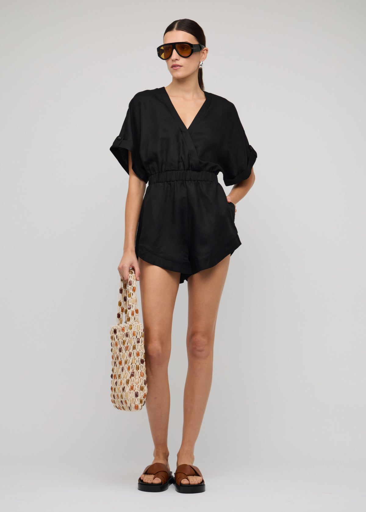 Model wearing Black Linen Blend V-neck Playsuit with a v-neckline with draped front.