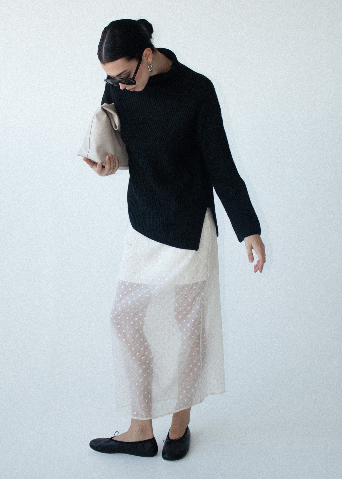 Model seated wearing Black Roll Neck Oversized Knit Jumper with side hem splits and long sleeves.