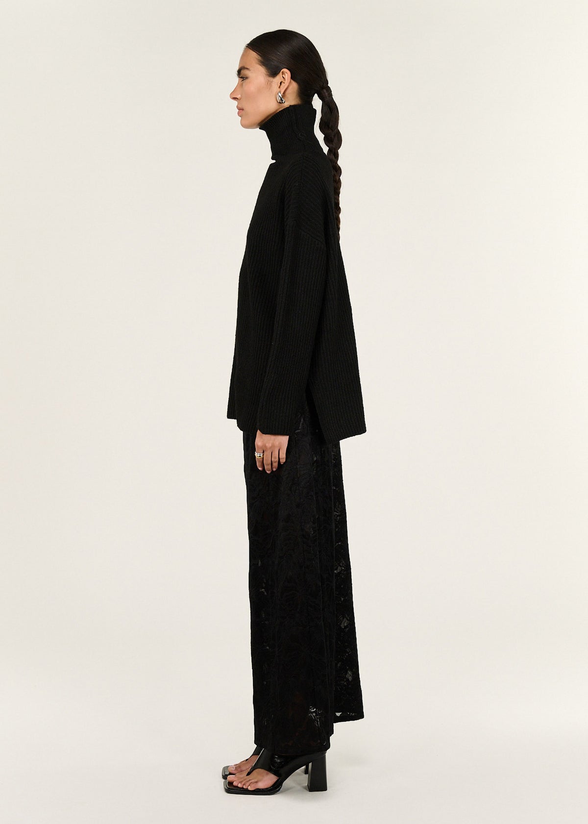 Side view of the Black Roll Neck Oversized Knit Jumper, showing side hem splits and long sleeves.