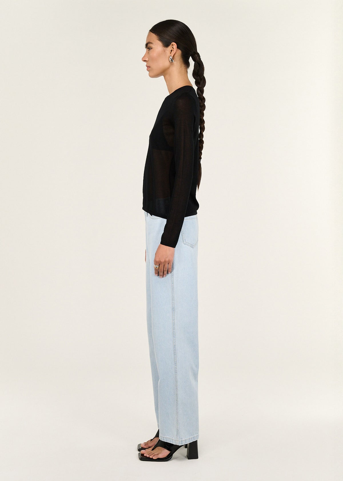 Side view of the Black Ruched Detail Sheer Knit Top, showing a sheer knit fabrication and a fitted silhouette.