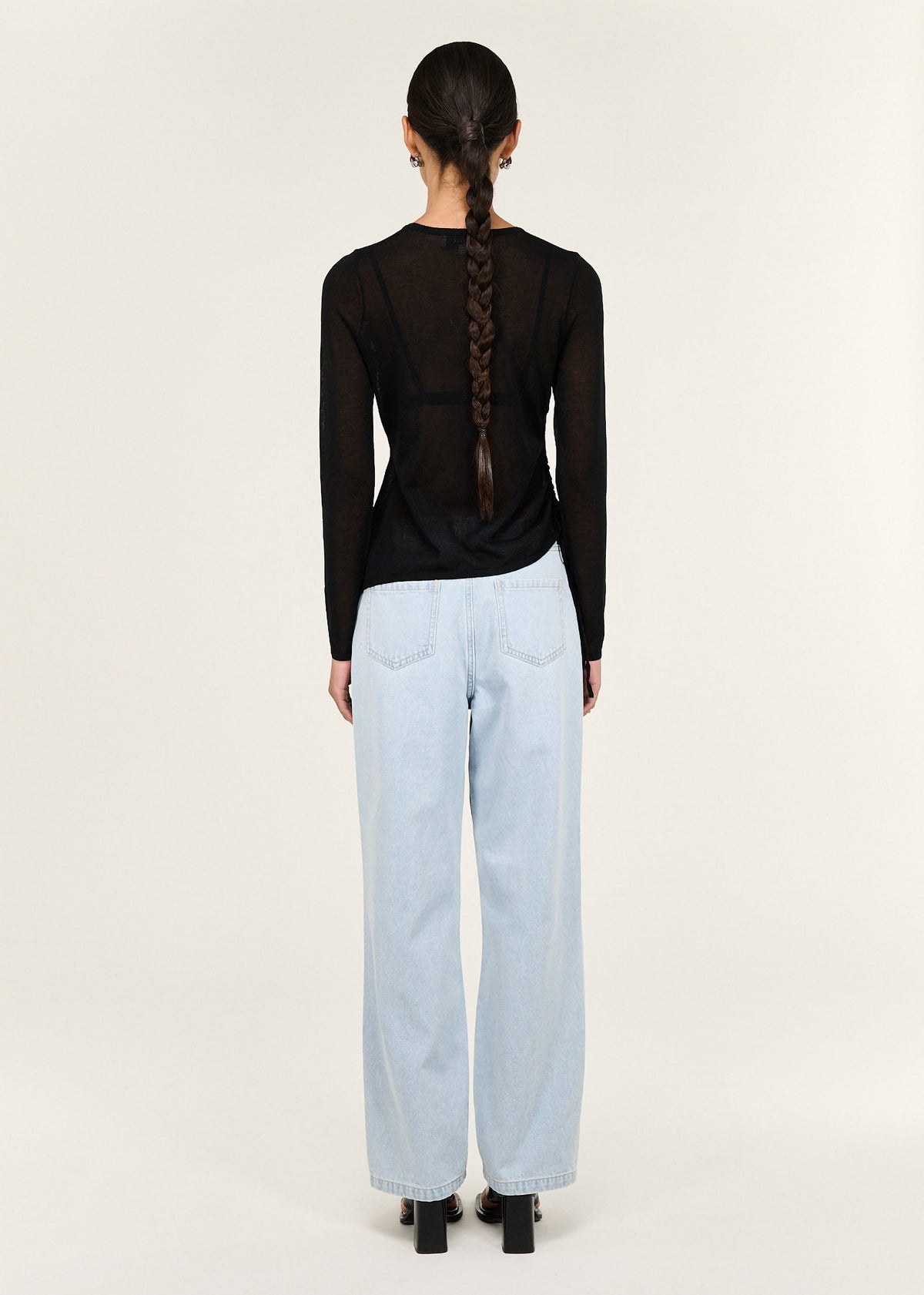 Back view of the Black Ruched Detail Sheer Knit Top with a sheer knit fabrication and a fitted silhouette.
