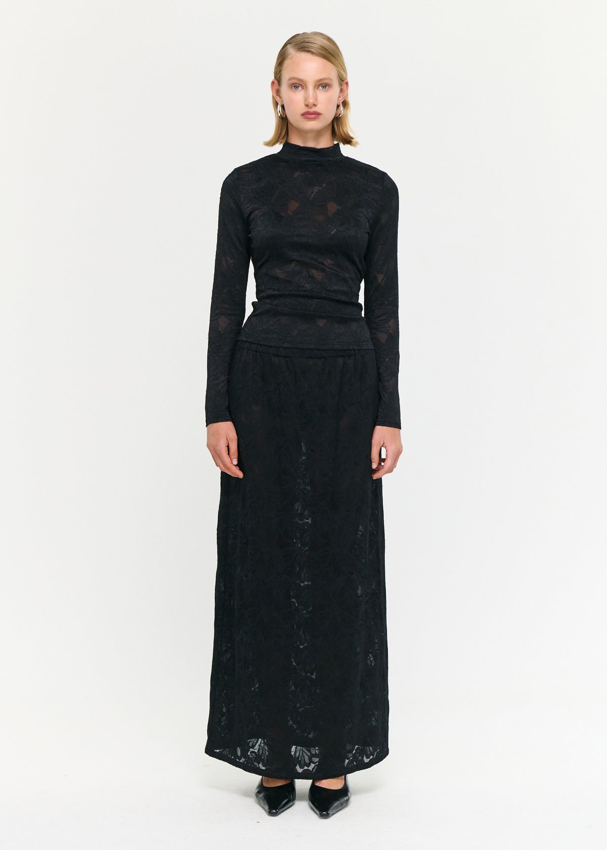 Model wearing Black Sheer Lace Long Sleeve Top with a high neckline and long sleeves.