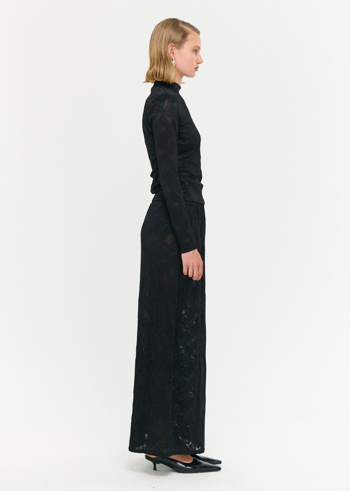 Side view of the Black Sheer Lace Long Sleeve Top, showing a high neckline and long sleeves.