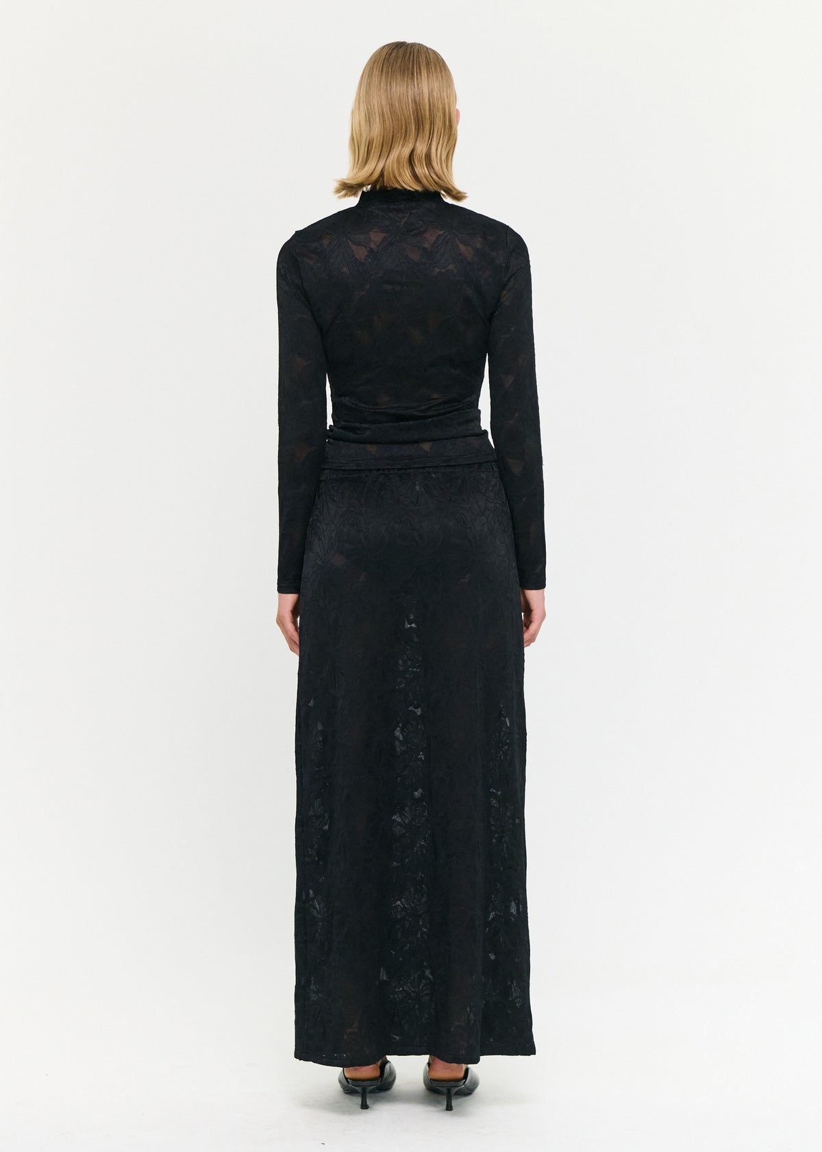 Back view of the Black Sheer Lace Long Sleeve Top with a sheer lace fabrication and a fitted silhouette.