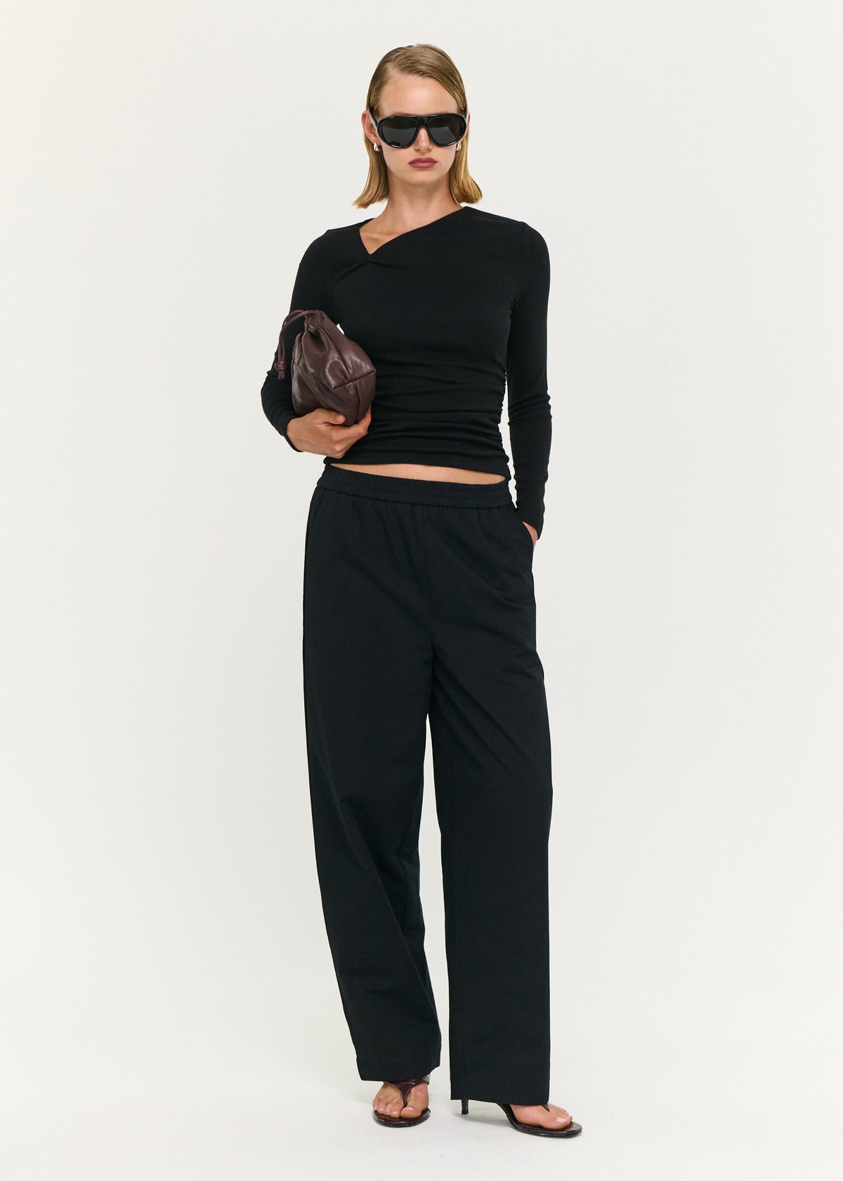 Model wearing Black Soft Jersey Twist Neck Top with a soft stretch fabrication and a fitted silhouette.