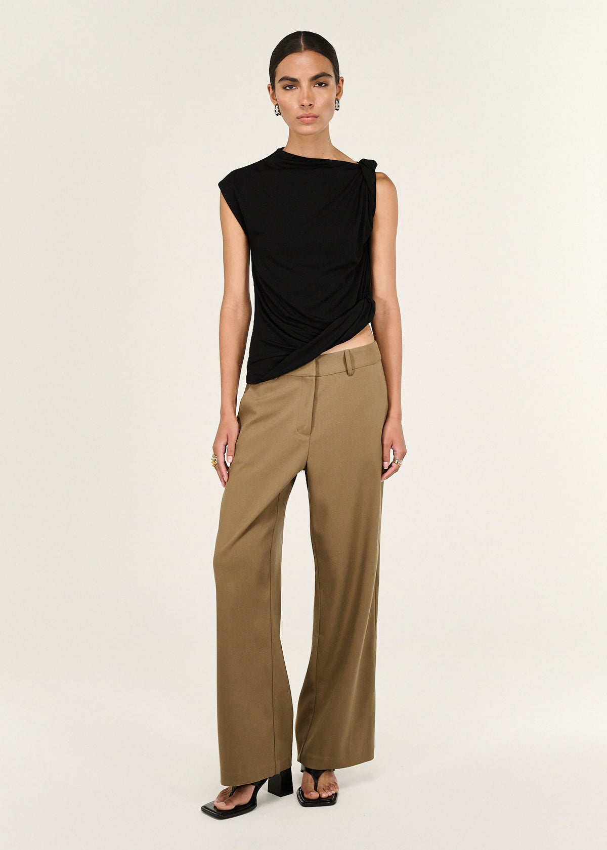 Model wearing Black Twist Asymmetric Tank with a shoulder twist detail and a draped silhouette.