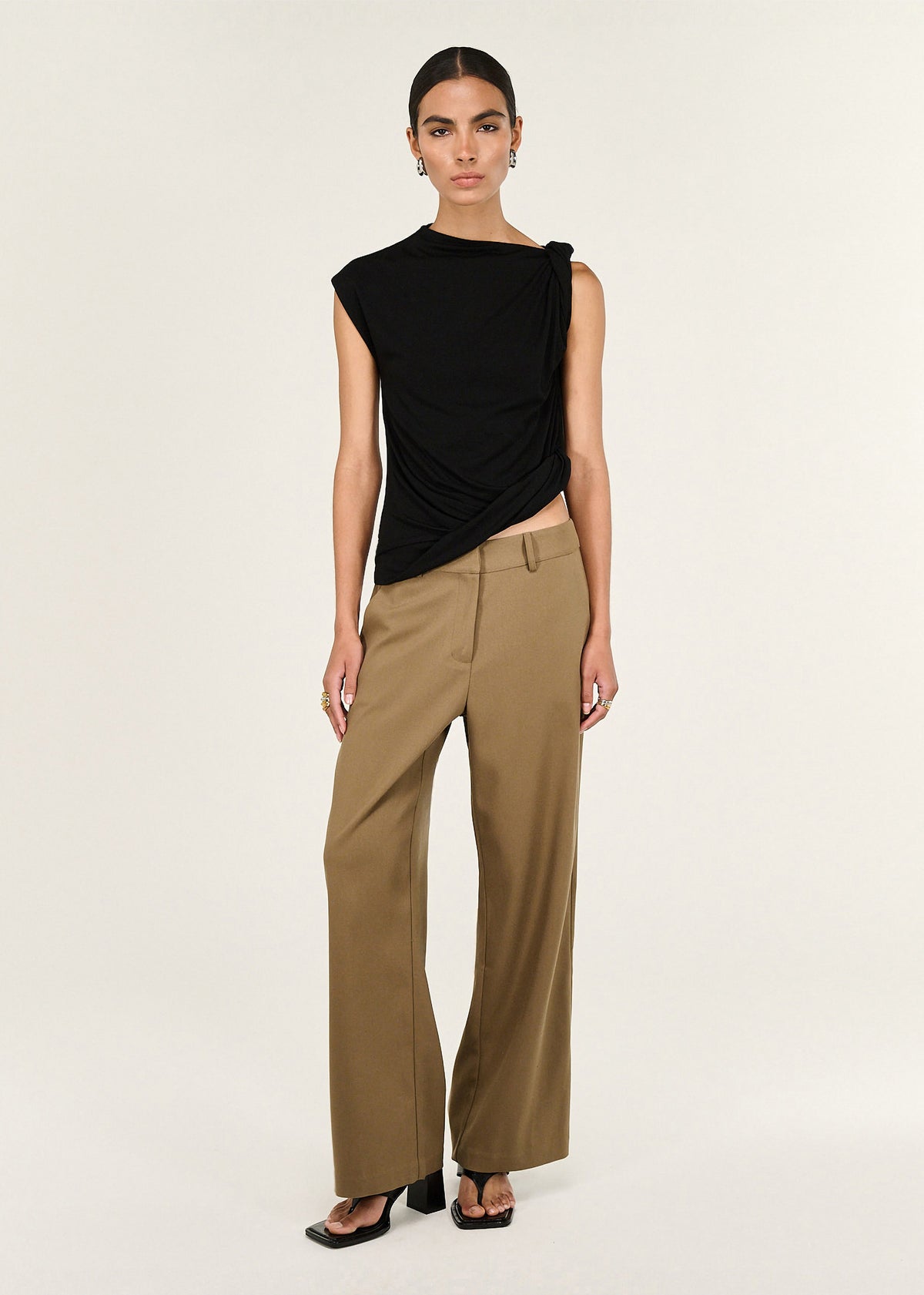 Model wearing Black Twist Asymmetric Tank with an asymmetric hem finish and a relaxed fit, turned to the side.