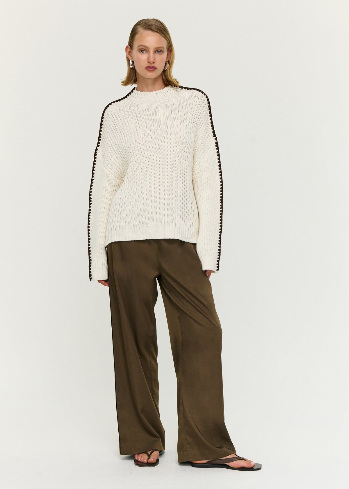 Model wearing Blanket Stitch Detail High Neck Jumper with a chunky rib knit fabrication and an oversized fit.