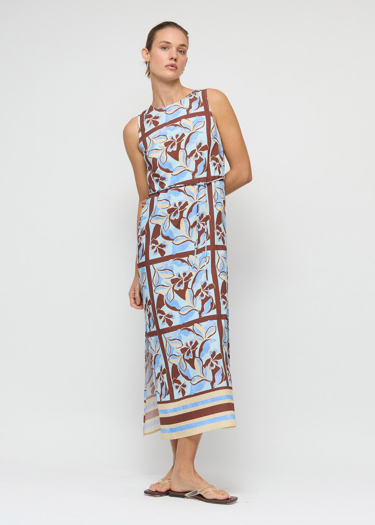 Model wearing Blue Abstract floral Midi Dress with Tie Waist with a sleeveless, high-neck silhouette and a midi length.