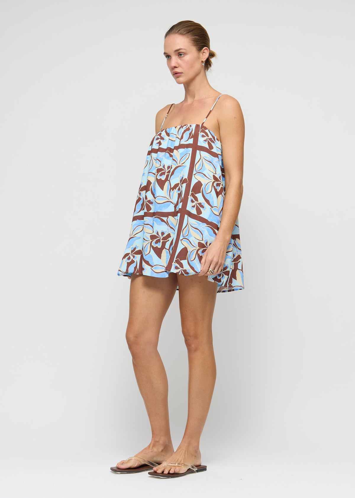 Model wearing Blue Abstract floral Mini Dress with a fully lined and a relaxed trapeze silhouette, turned to the side.