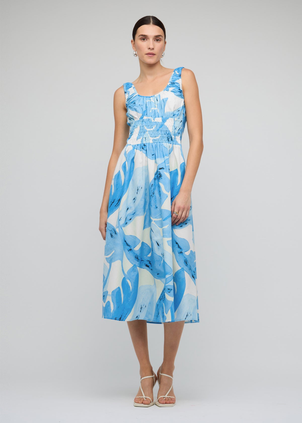 Model wearing Blue and White Floral Cotton Shirred Midi Dress with a midi length with shirred waist detail.