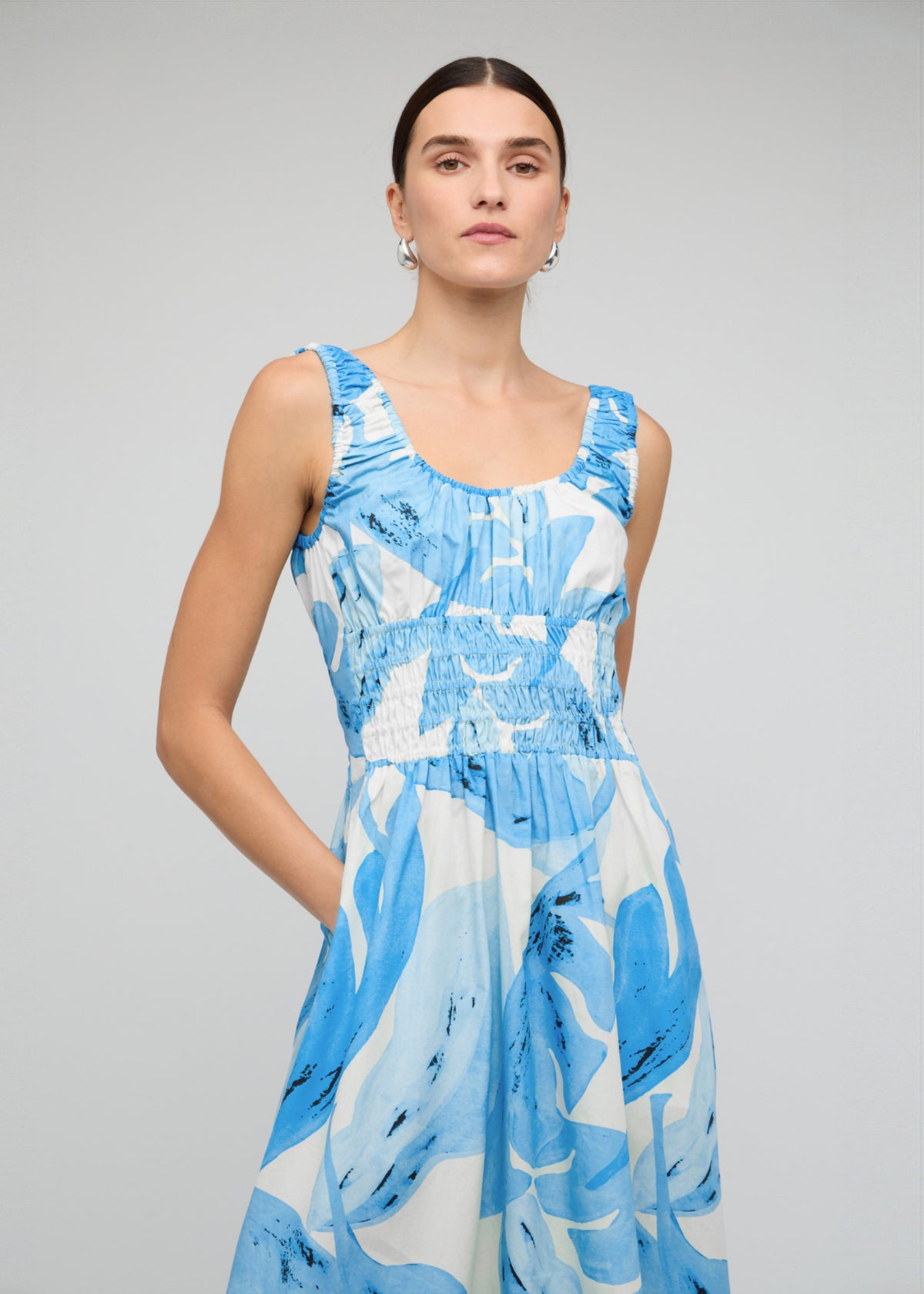 Model wearing Blue and White Floral Cotton Shirred Midi Dress, showing a midi length with shirred waist detail.