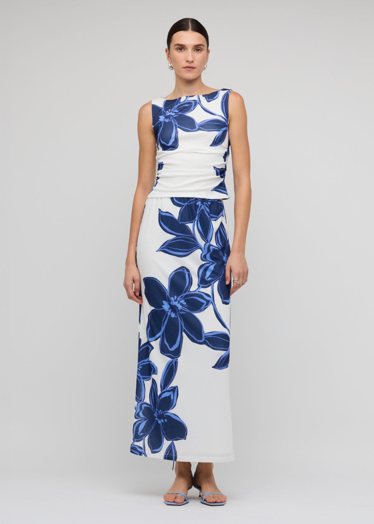 Model wearing Blue and White Floral Mesh Maxi Skirt with a maxi length with back split and a blue floral mesh print.