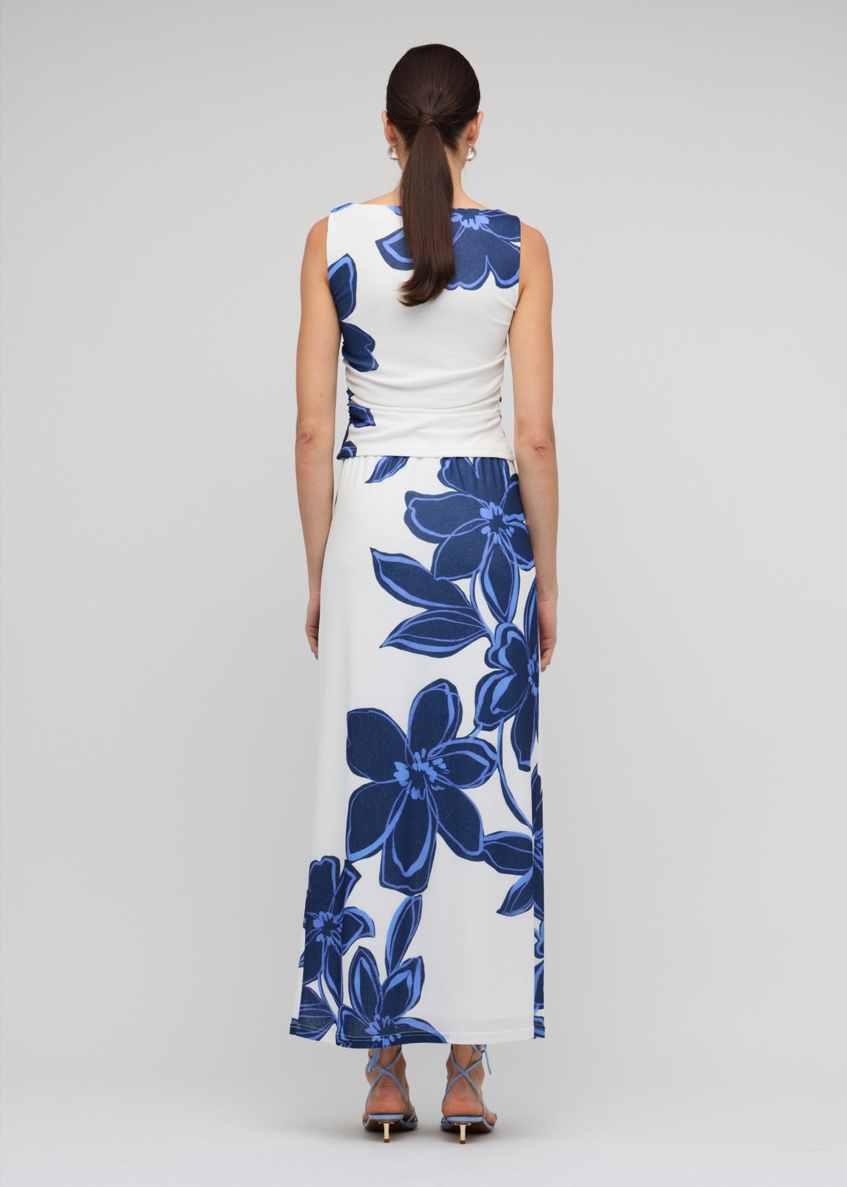 Back view of the Blue and White Floral Mesh Maxi Skirt with a maxi length with back split and a blue floral mesh print.