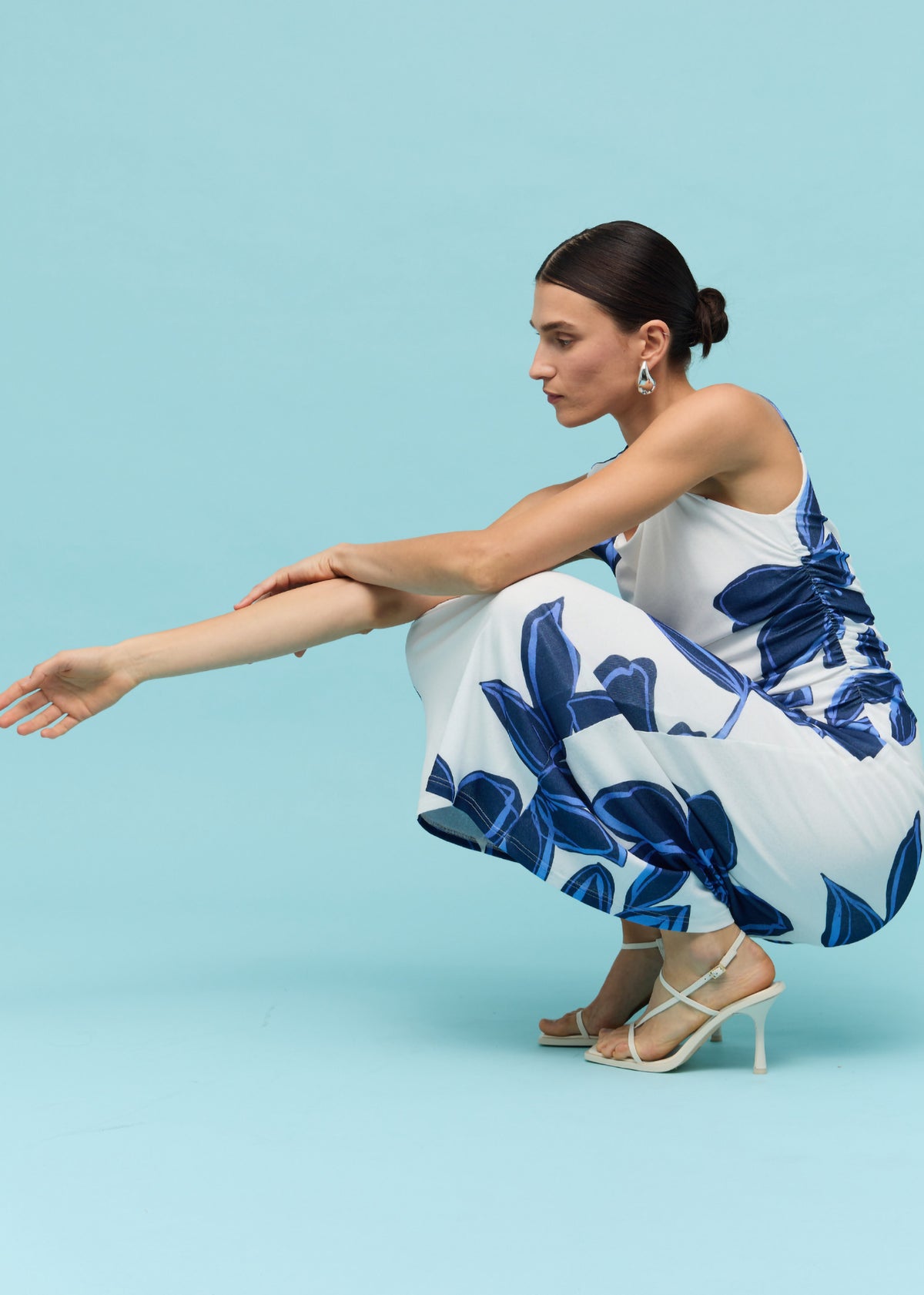 Model seated wearing Blue and White Floral Mesh Midi Dress with a fully lined with stretch and a blue oversized floral print.