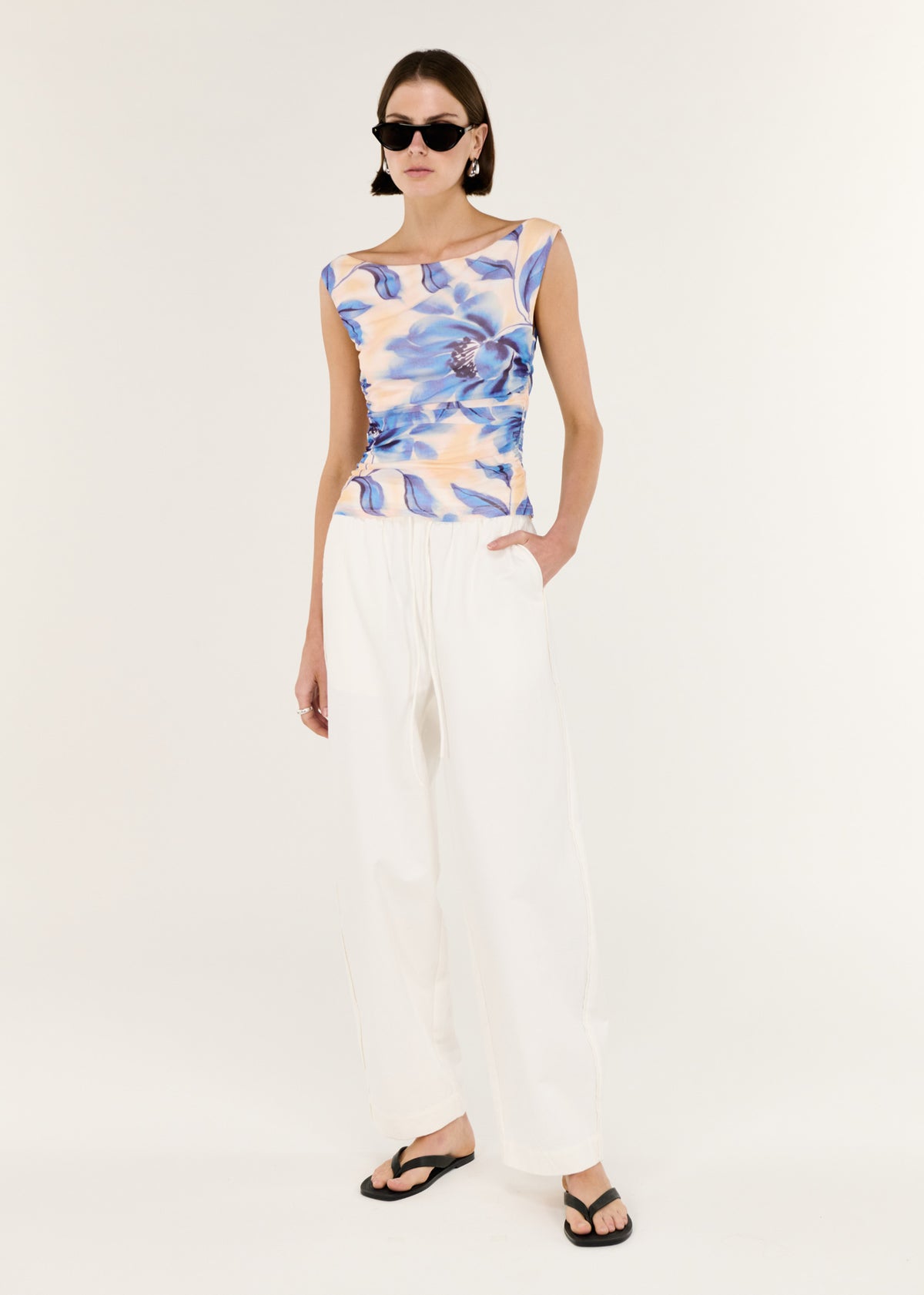 Model wearing Blue Blurred Floral Mesh Top with a soft blurred floral print and a subtle ruching through the waist.