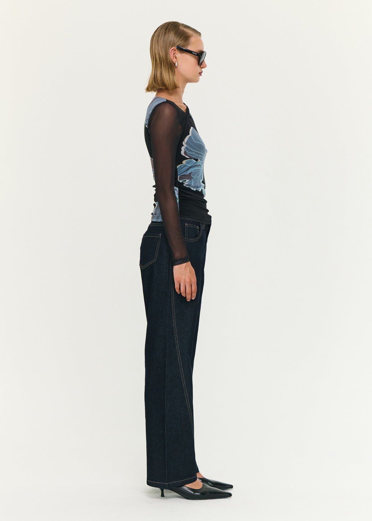 Side view of the Blue Floral Asymmetric Neck Mesh Top, showing a fitted silhouette and an asymmetrical neckline detail.