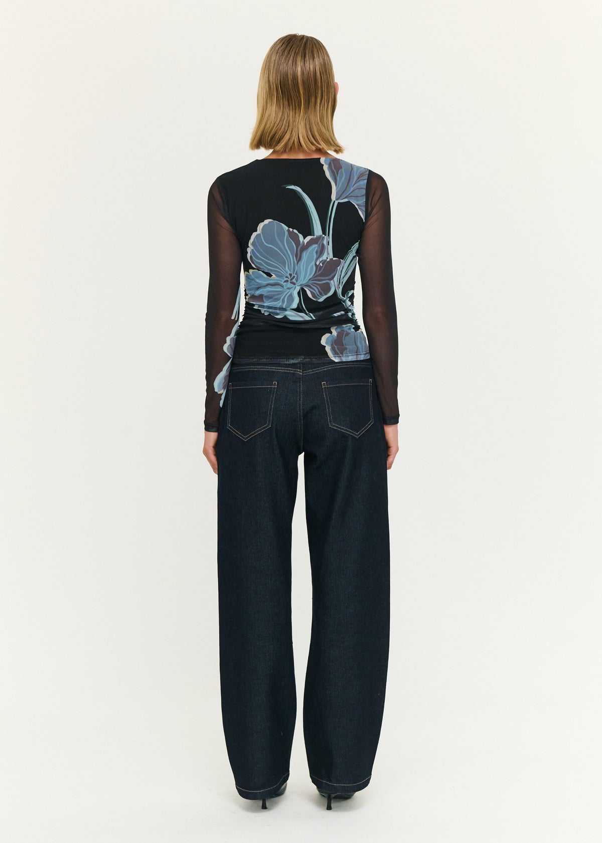 Back view of the Blue Floral Asymmetric Neck Mesh Top with a sheer mesh fabrication and a fitted silhouette.