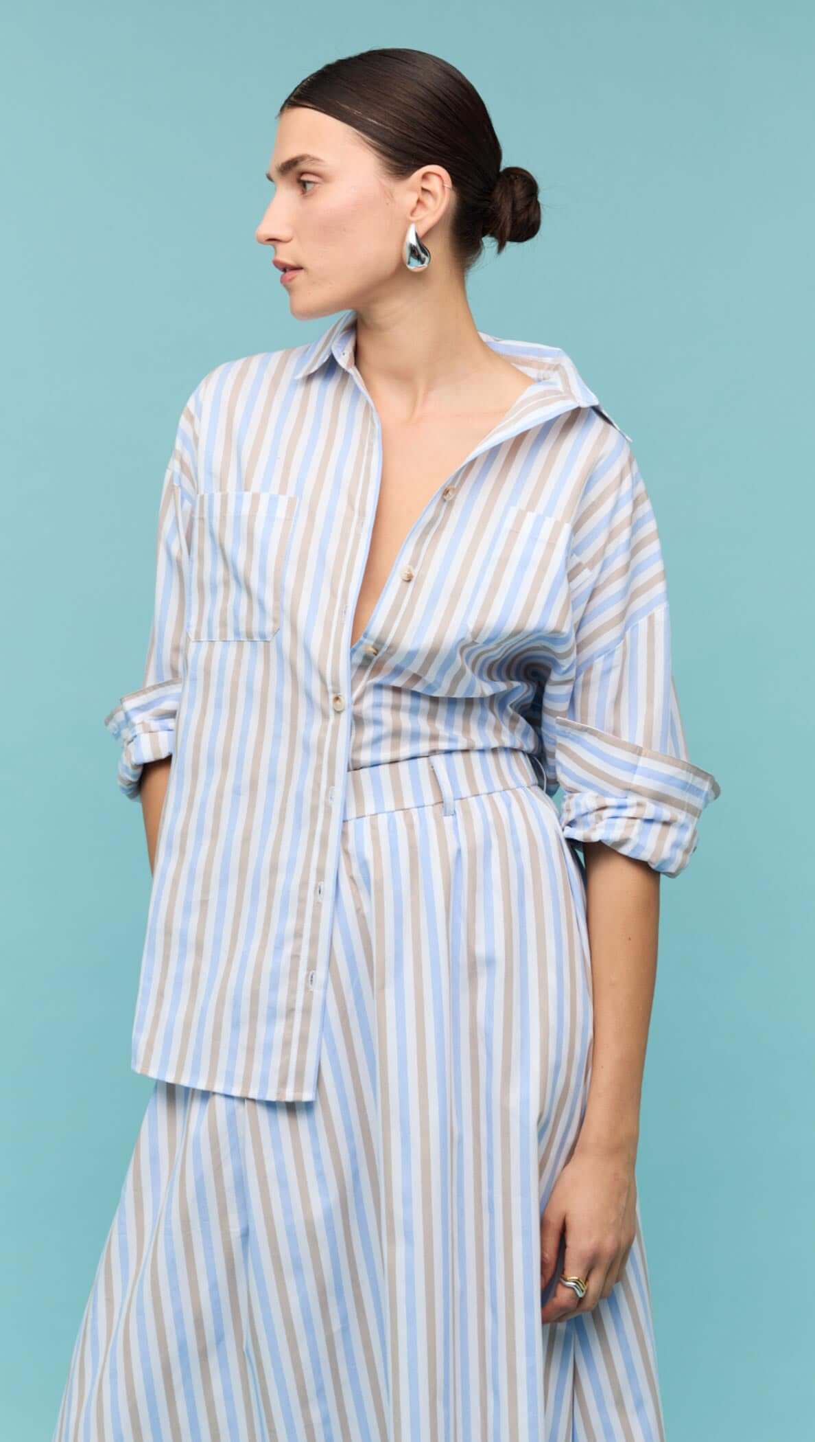Blue Stripe Cotton A-Line Maxi Skirt worn with a matching striped shirt against a turquoise background.