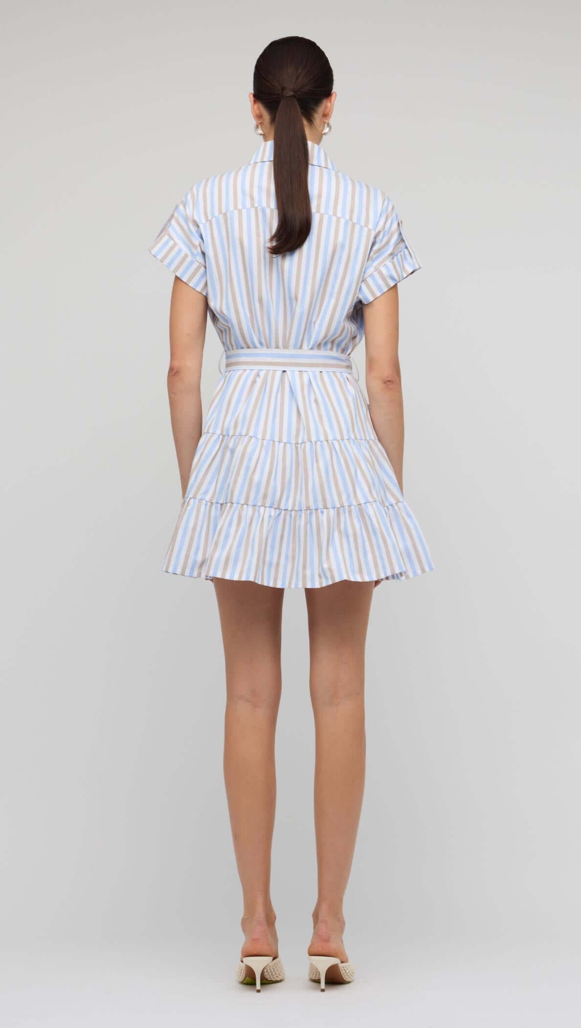 Back view of the Blue Stripe Cotton Mini Shirt Dress, featuring short sleeves, tie waist, and tiered mini skirt.