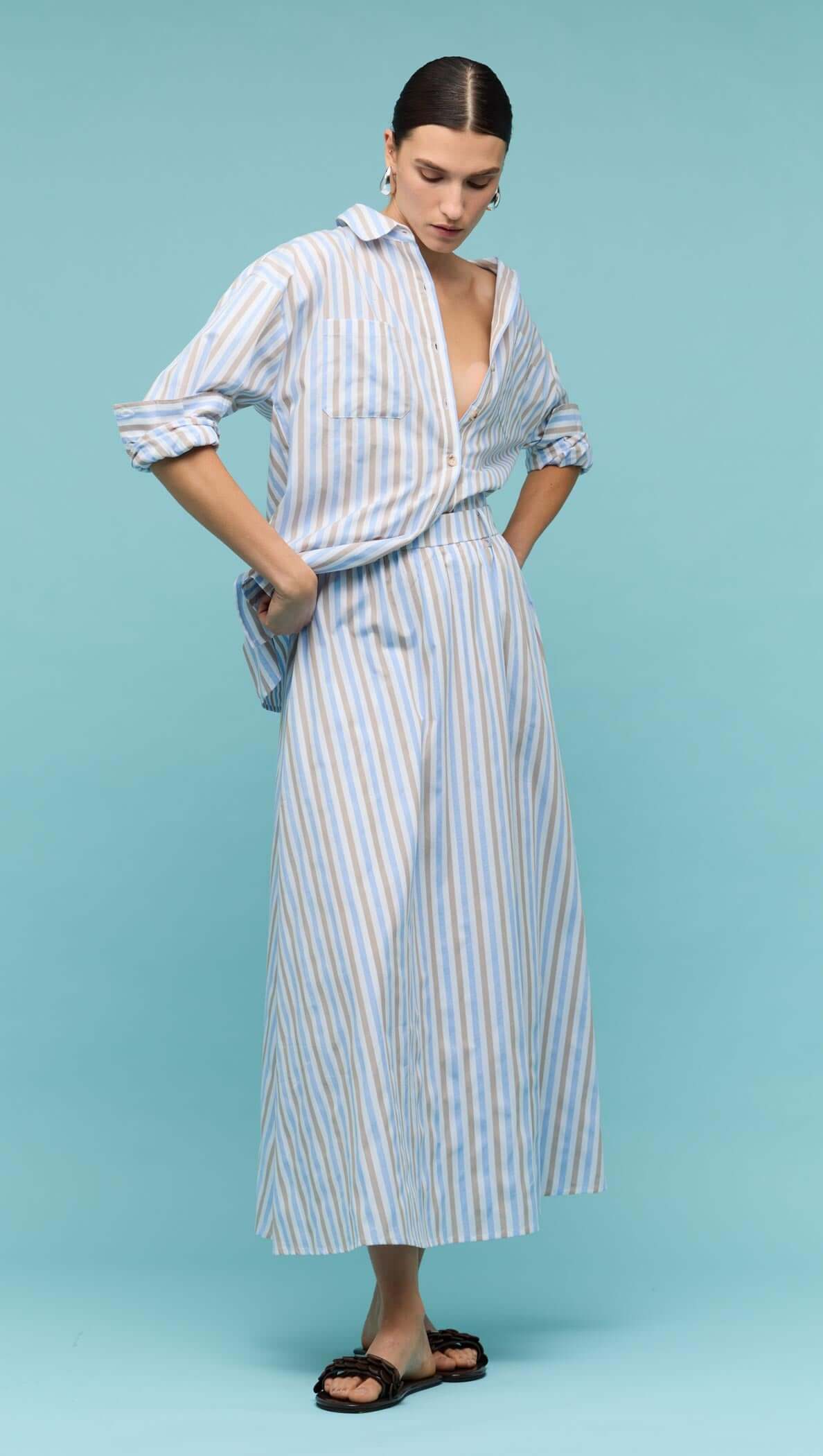 Model wearing a Blue Stripe Cotton Oversize Shirt with matching striped skirt on a blue background.