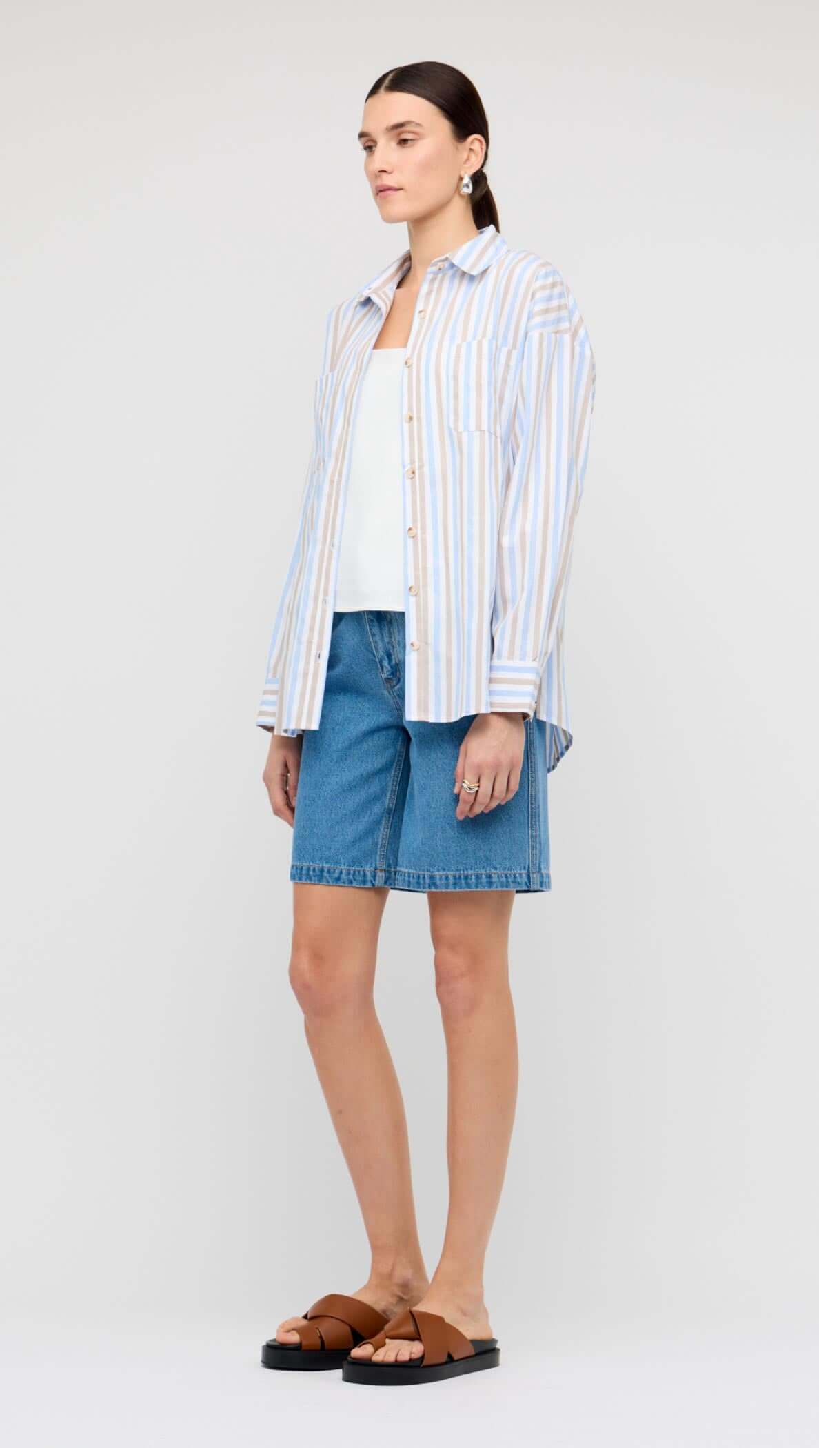 Model wearing a Blue Stripe Cotton Oversize Shirt with denim shorts and sandals.