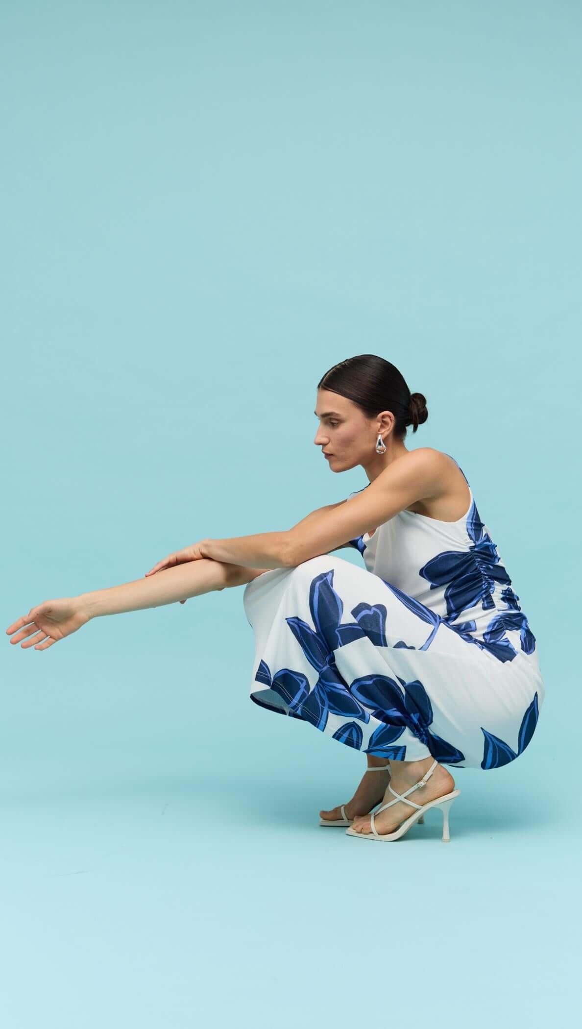 Model wearing Blue & White Floral Mesh Midi Dress, showcasing floral print and stylish silhouette against a solid blue background.