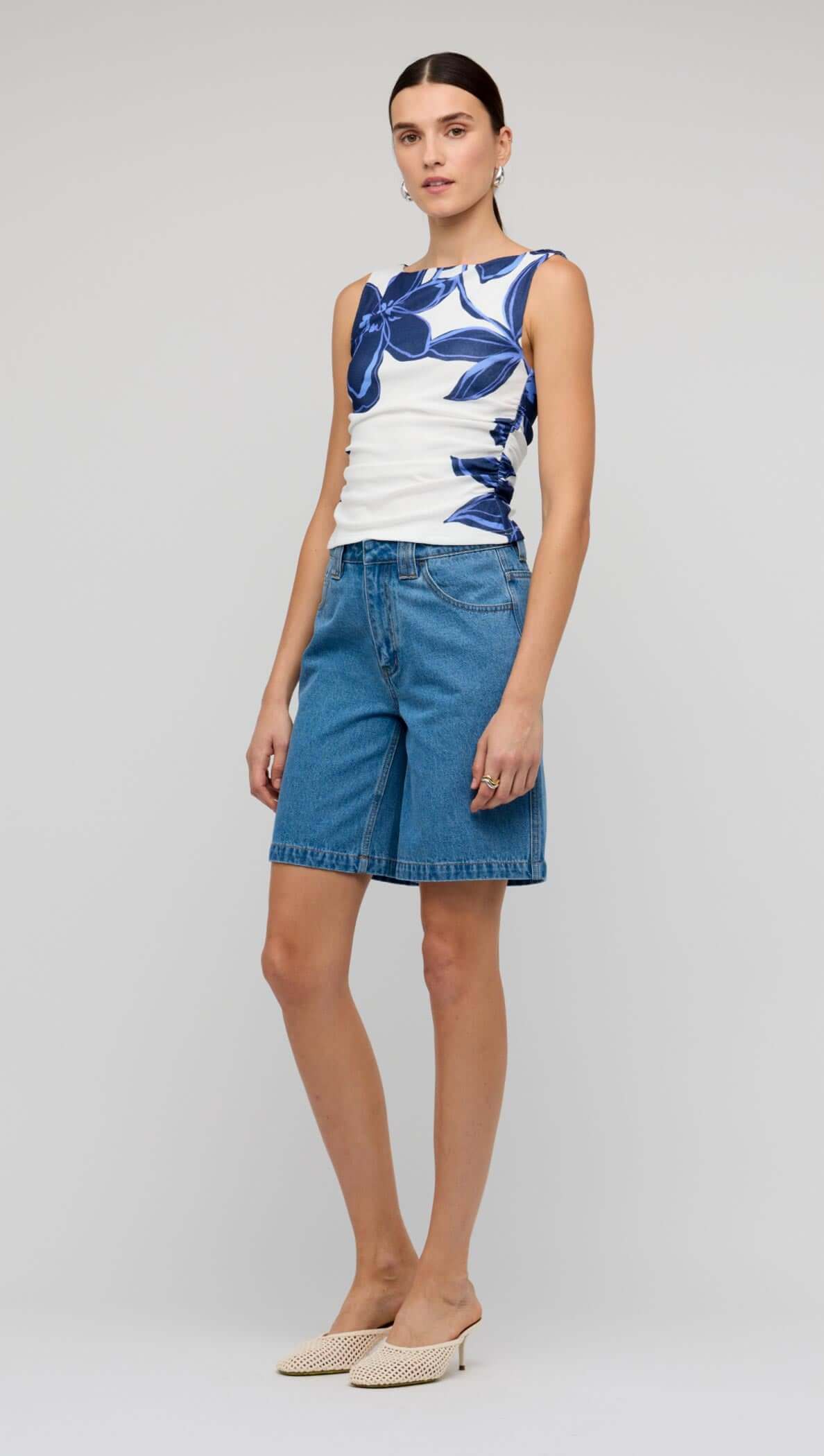 Model wearing the Blue & White Floral Mesh Top with denim shorts, showcasing a stylish summer look.