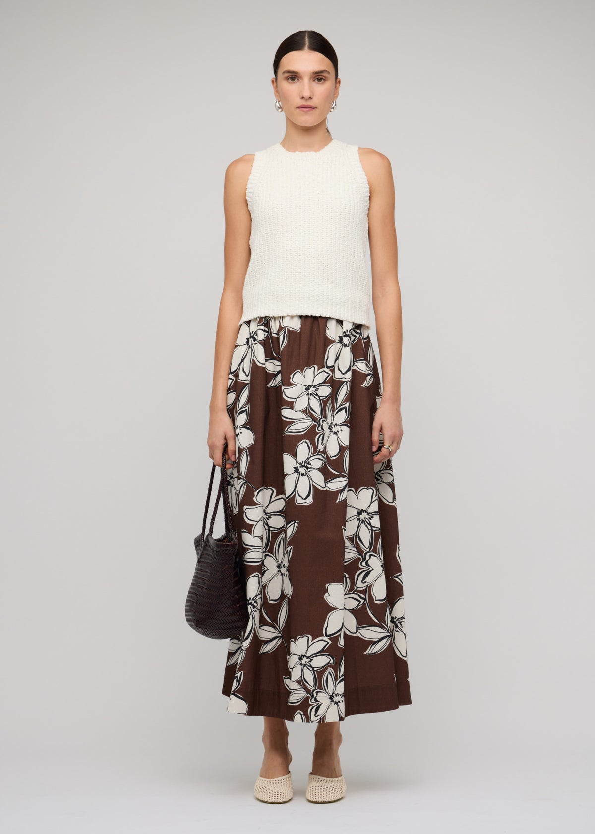 Model wearing Brown and White Cotton Floral A-Line Maxi Skirt with a chocolate brown with white floral print and an elasticated waistband.