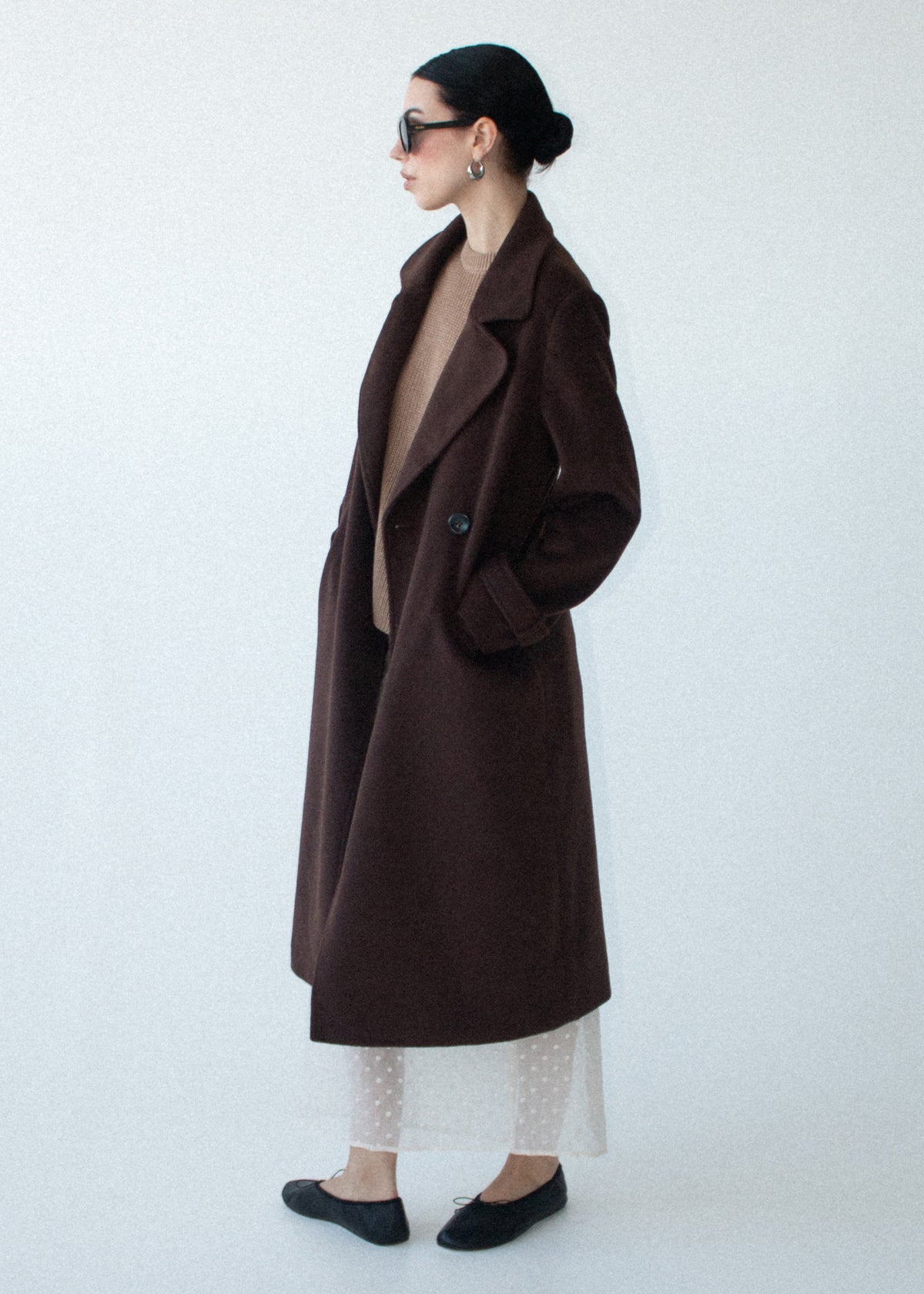 Side view of the Brown Double-Breasted Longline Coat, showing functional front flap pockets and a back vent.