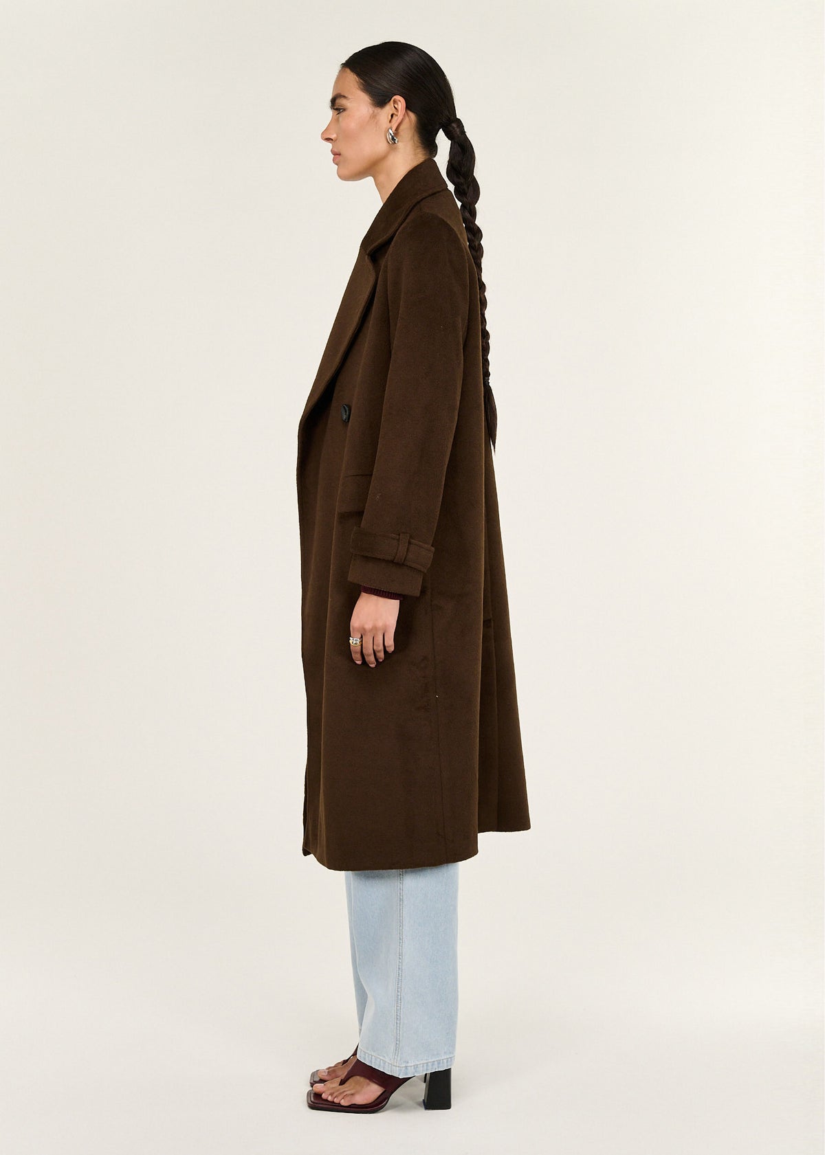 Side view of the Brown Double-Breasted Longline Coat, showing a back vent and functional front flap pockets.