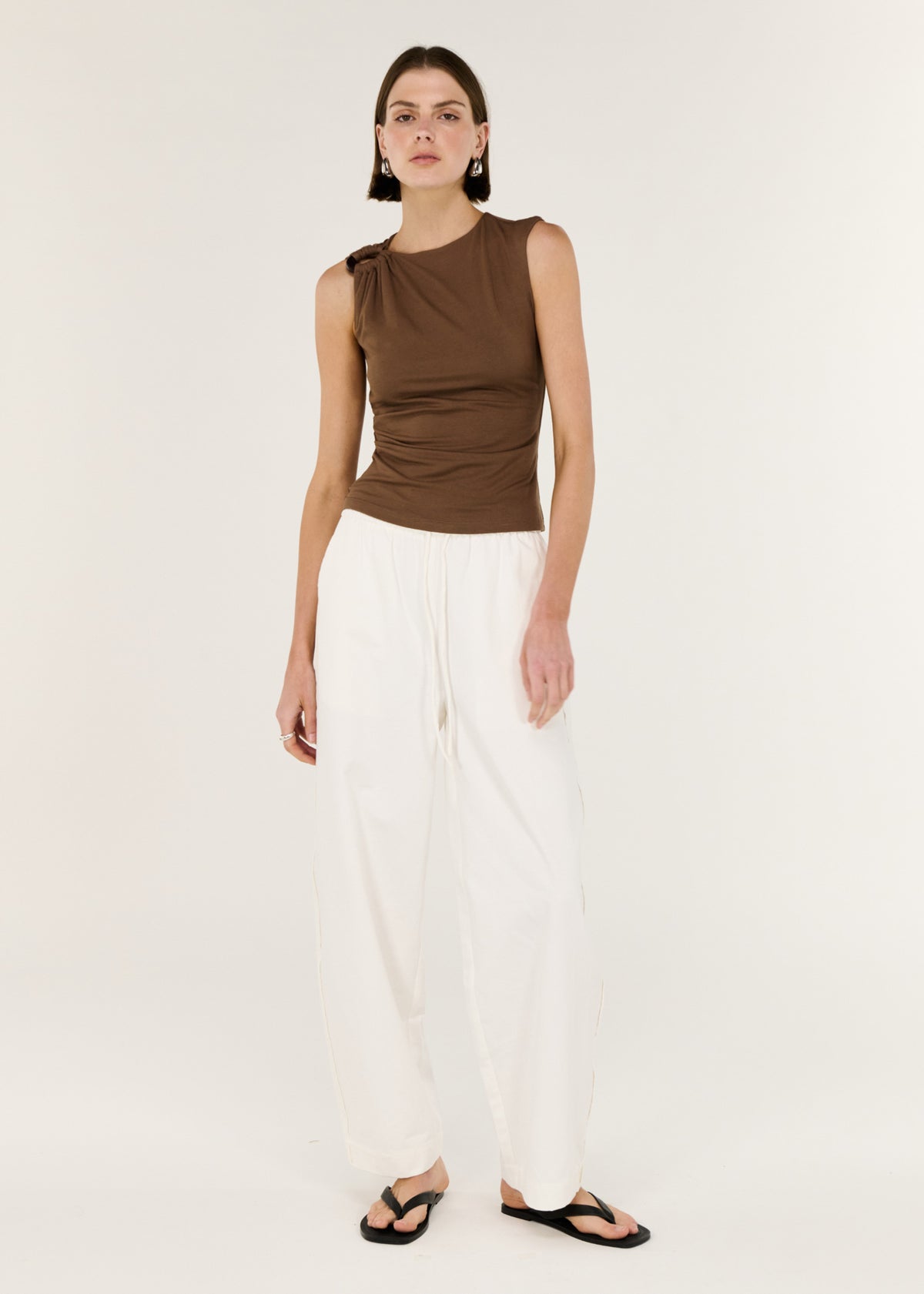 Model wearing Brown Ruched Slinky Tank, showing a statement hardware shoulder detail and a soft ruching through the body.