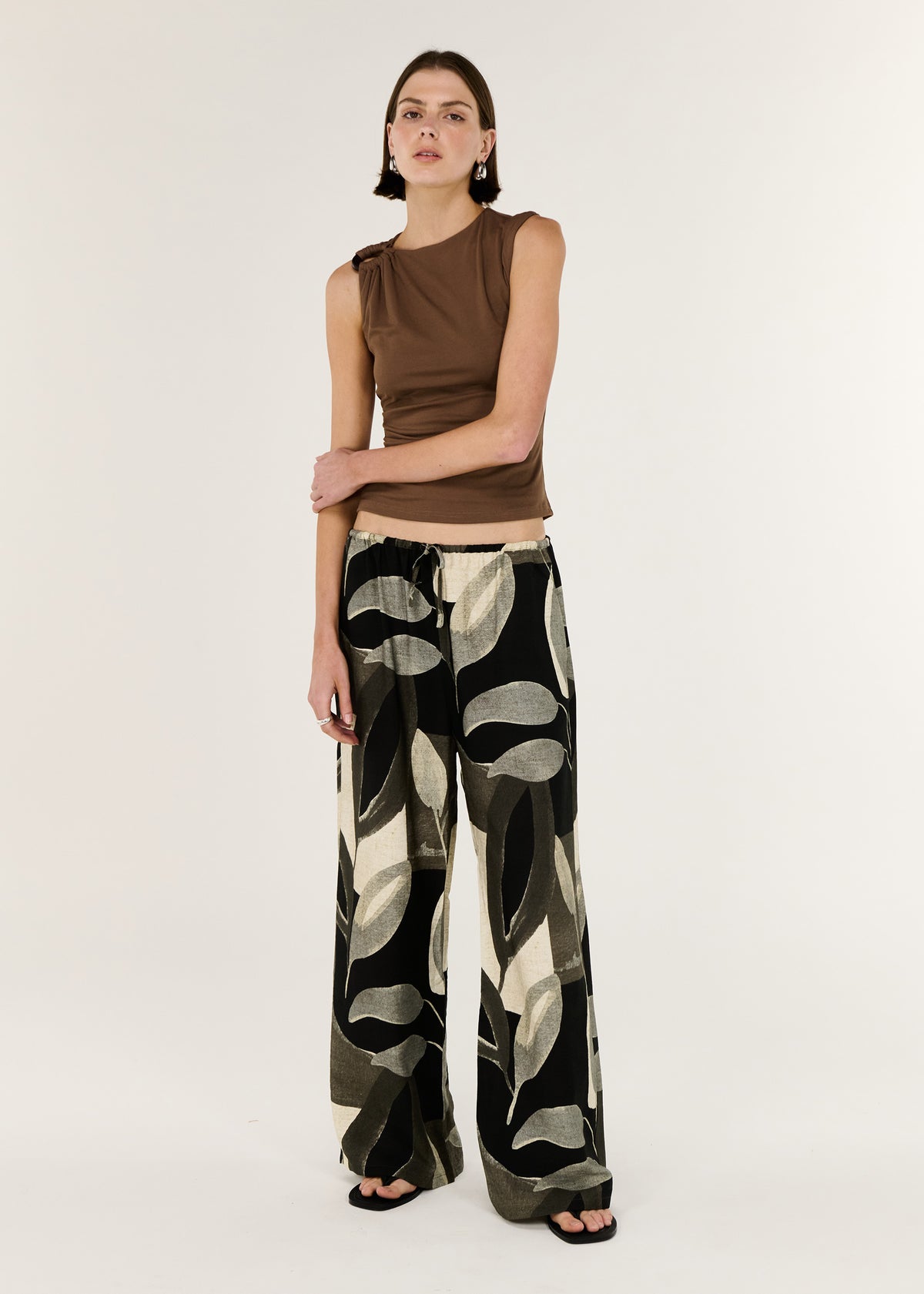 Model wearing Brown Ruched Slinky Tank with a sleeveless cut and a statement hardware shoulder detail.
