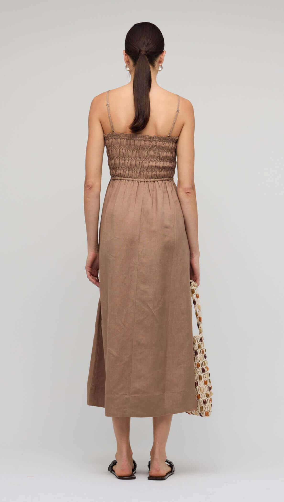 Model wearing the Brown Shirred Cut-Out Linen Midi Dress, showcasing the back detail and flowy skirt.