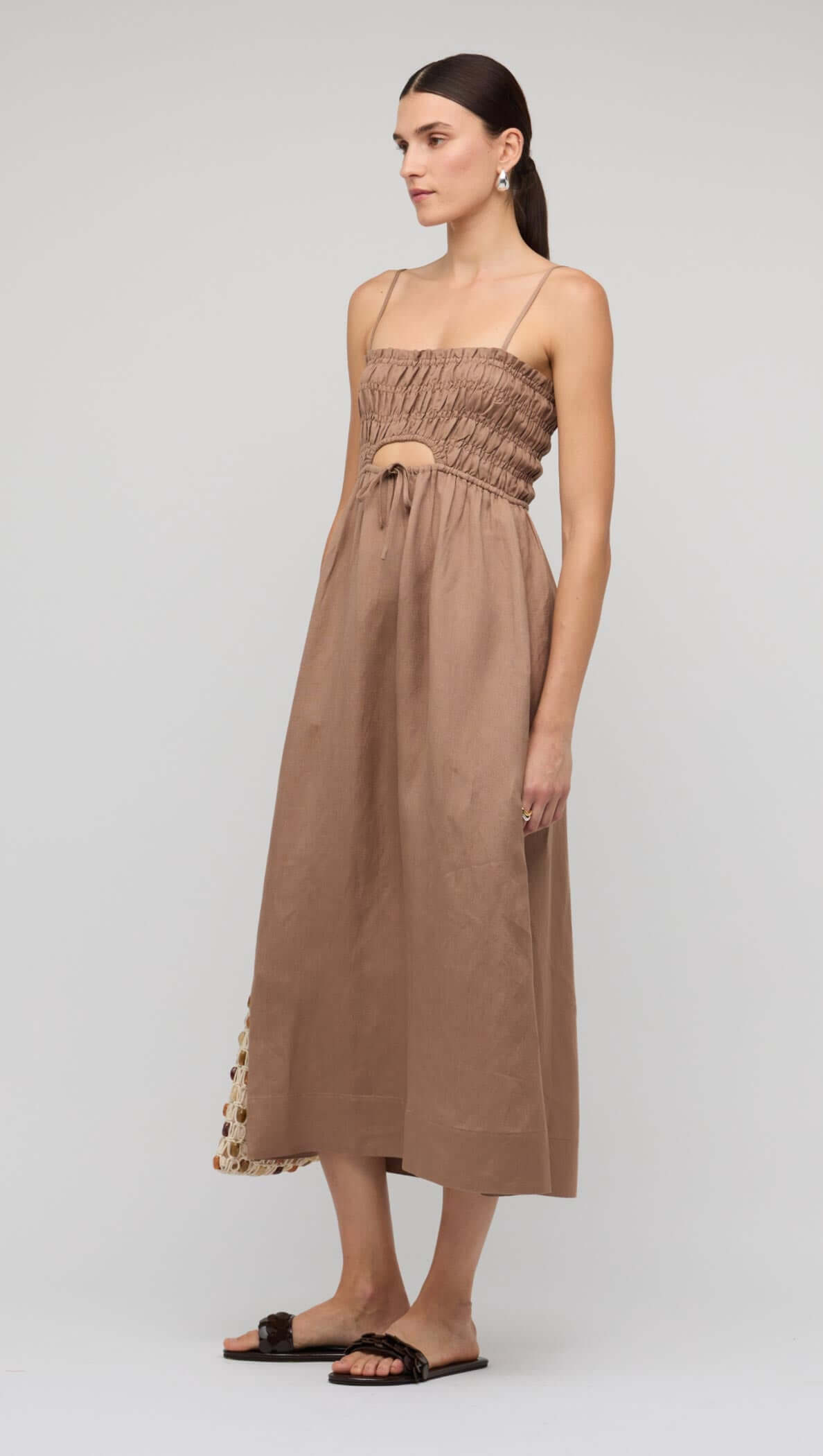 Brown Shirred Cut-Out Linen Midi Dress worn by model with a bag in a neutral background.